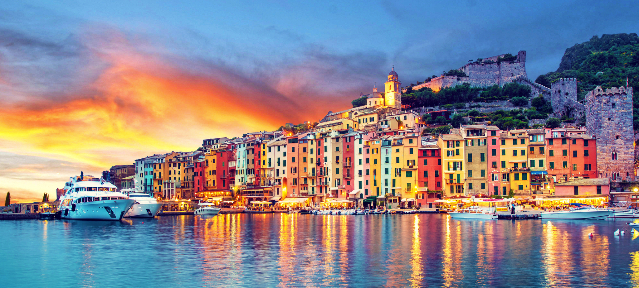 Portovenere Küstenstadt mit bunten Häusern und Booten bei Sonnenuntergang.