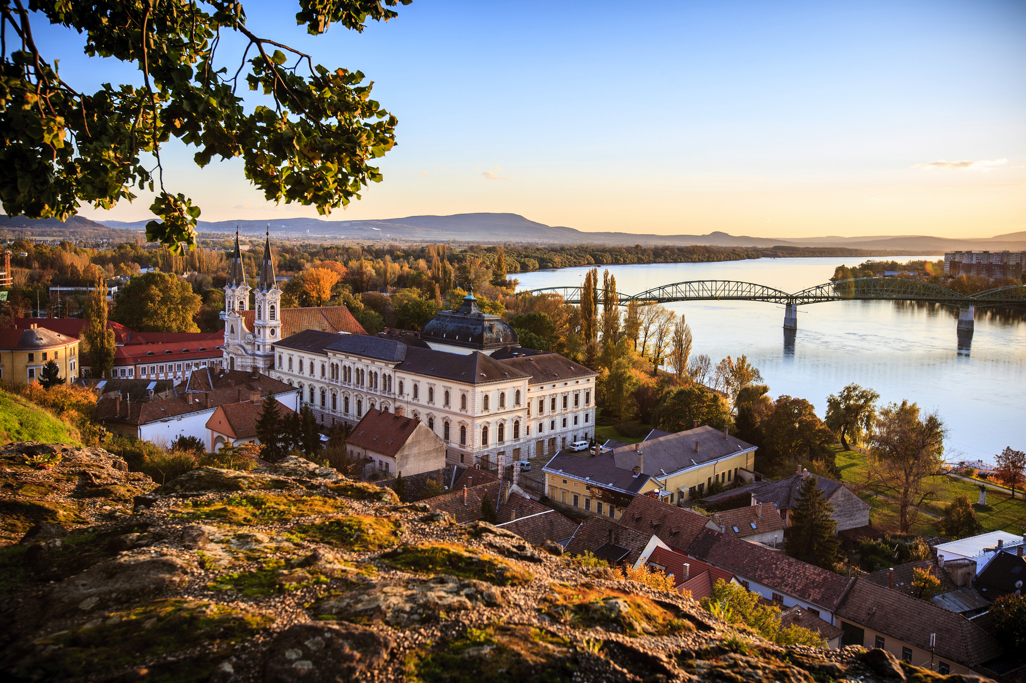 Flusslandschaft mit Brücke und historischem Gebäude bei Sonnenaufgang.