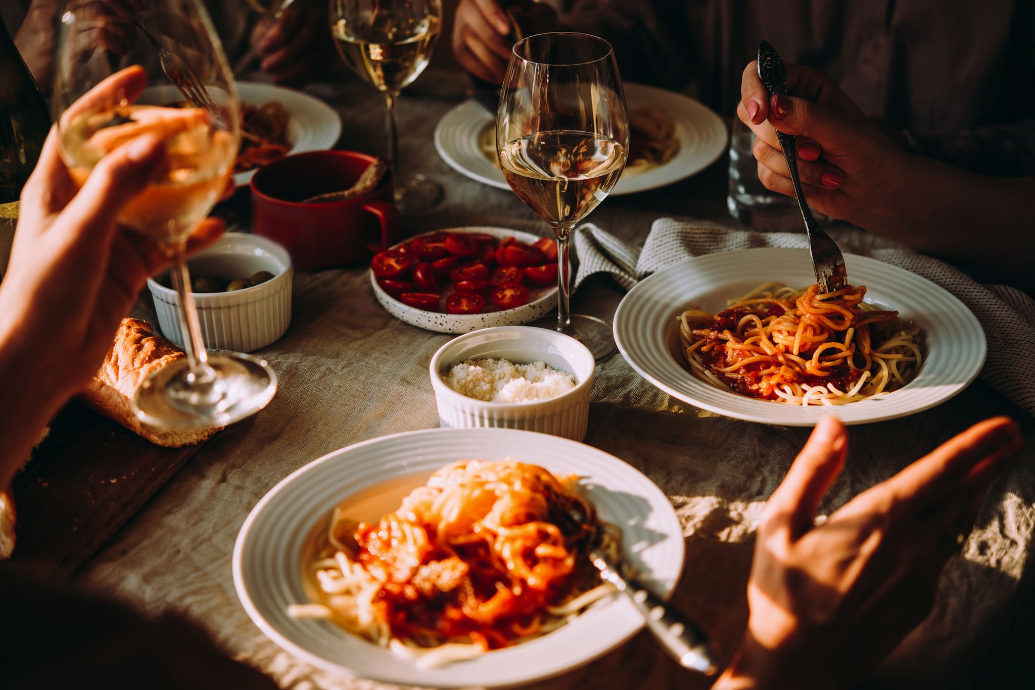 Personen essen Pasta bei einem geselligen Abendessen.