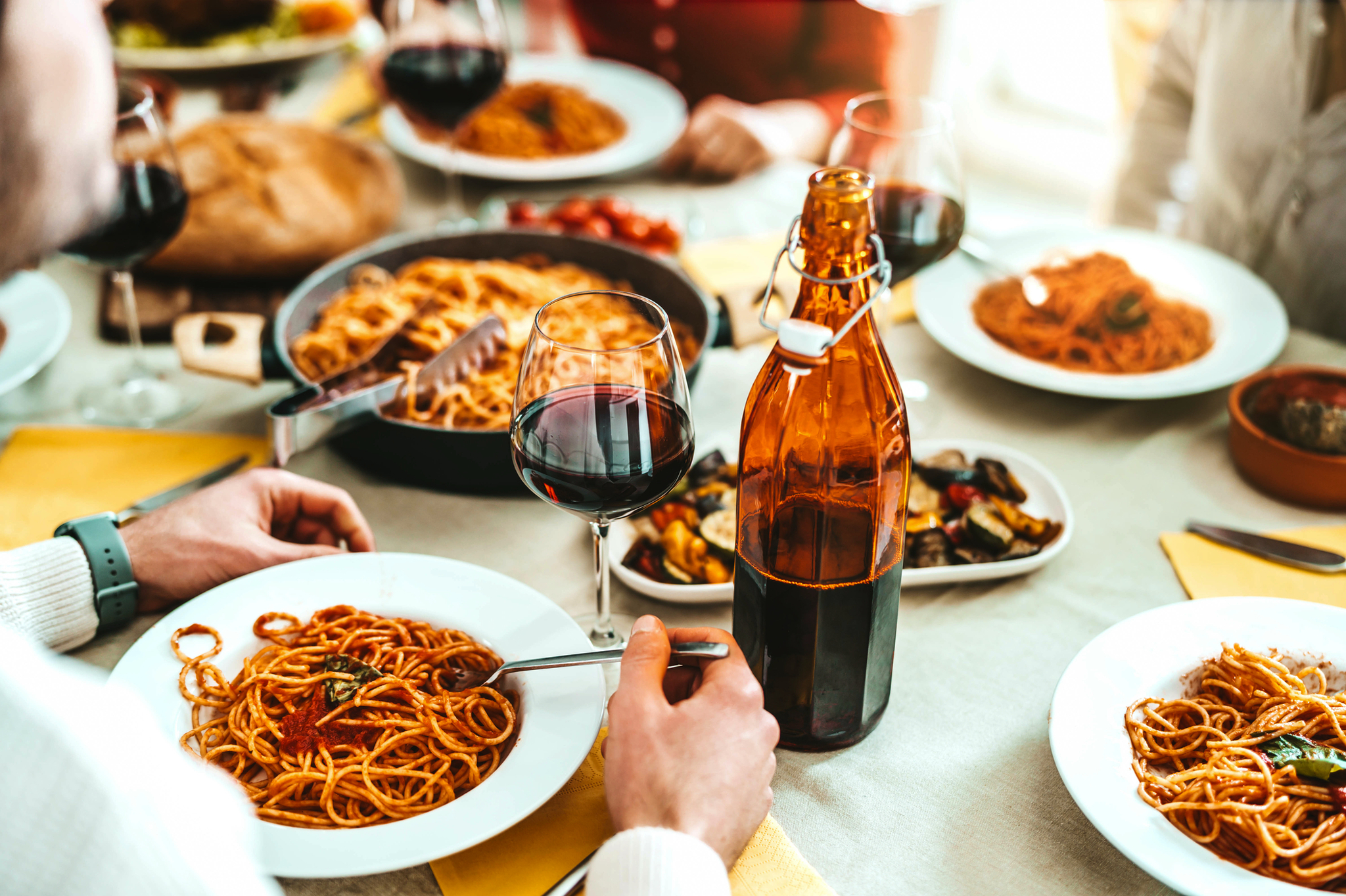 Gruppe von Freunden, die in einem italienischen Restaurant Spaghetti und Rotwein genießen.