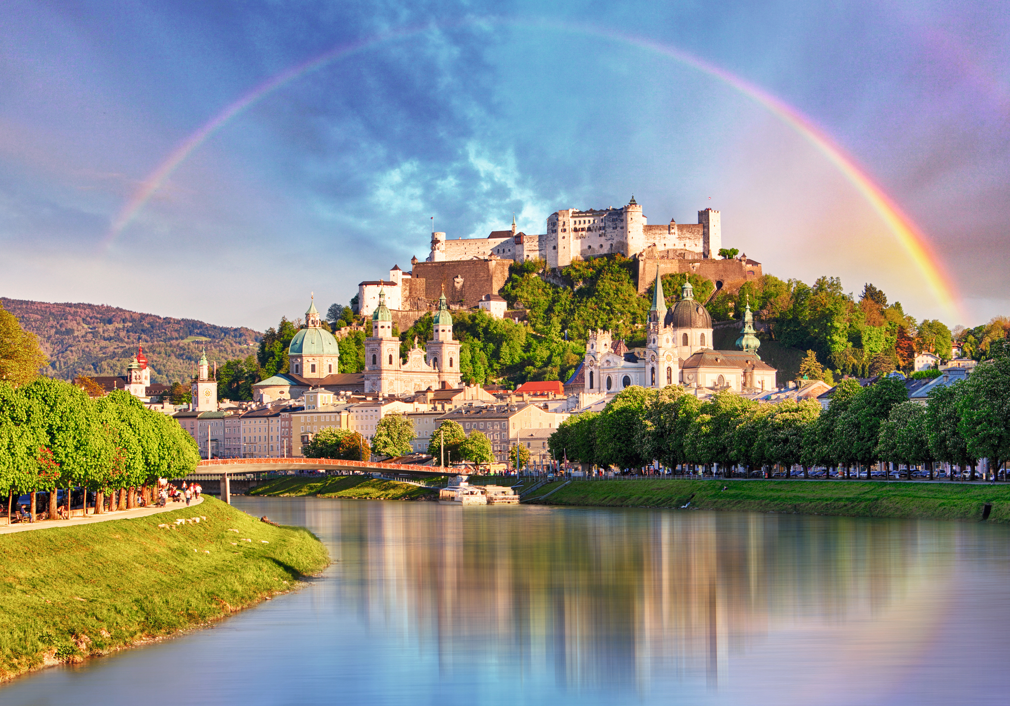 Stadtansicht von Salzburg mit Festung Hohensalzburg unter einem Regenbogen.