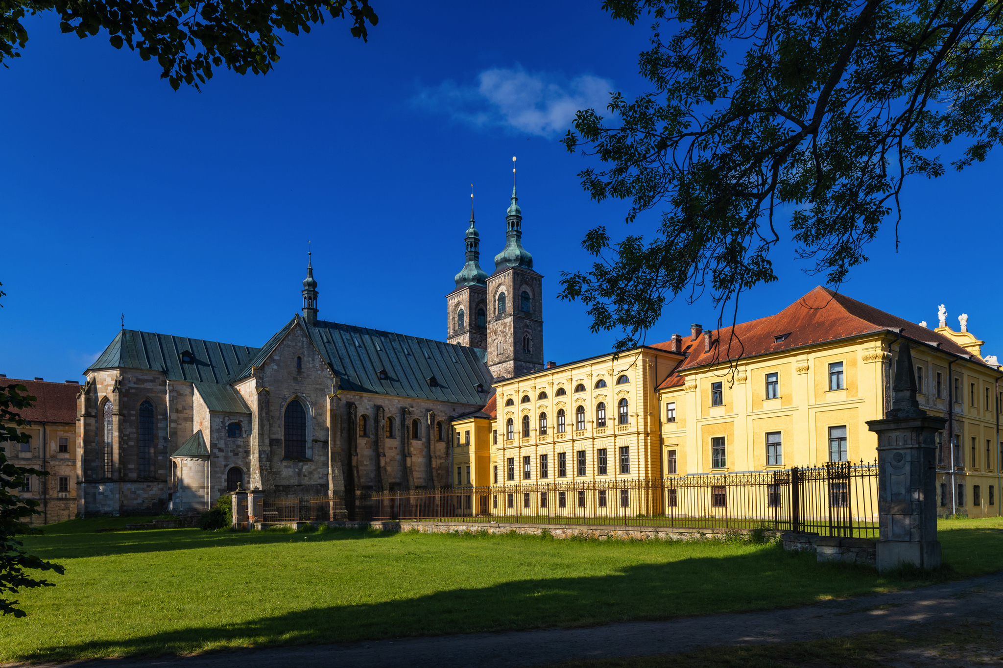 Kirche und historisches Gebäude bei sonnigem Wetter mit blauem Himmel im Hintergrund.