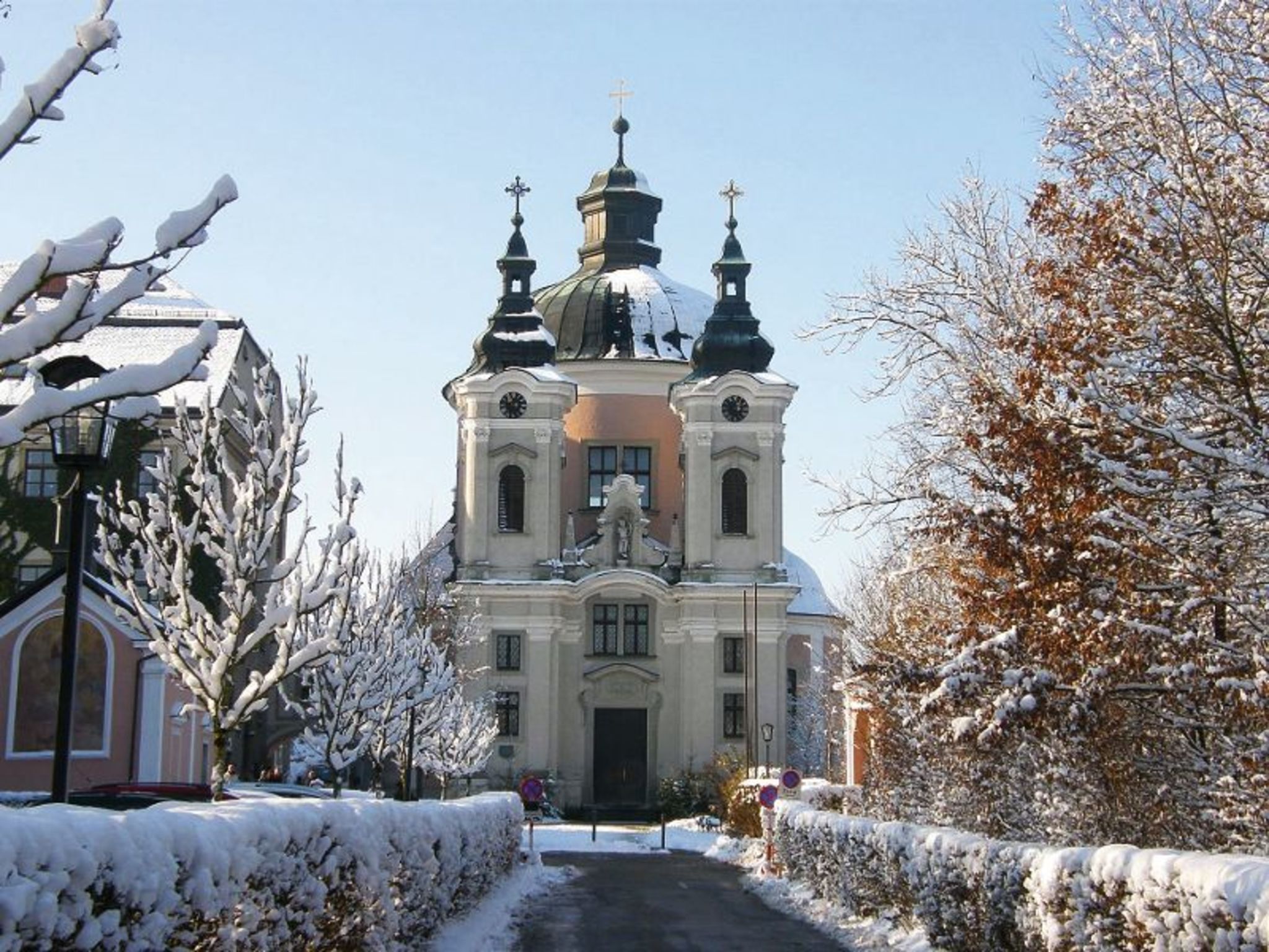 Wallfahrtskirche Christkindl im Winter mit Schnee auf Bäumen und Wegen.