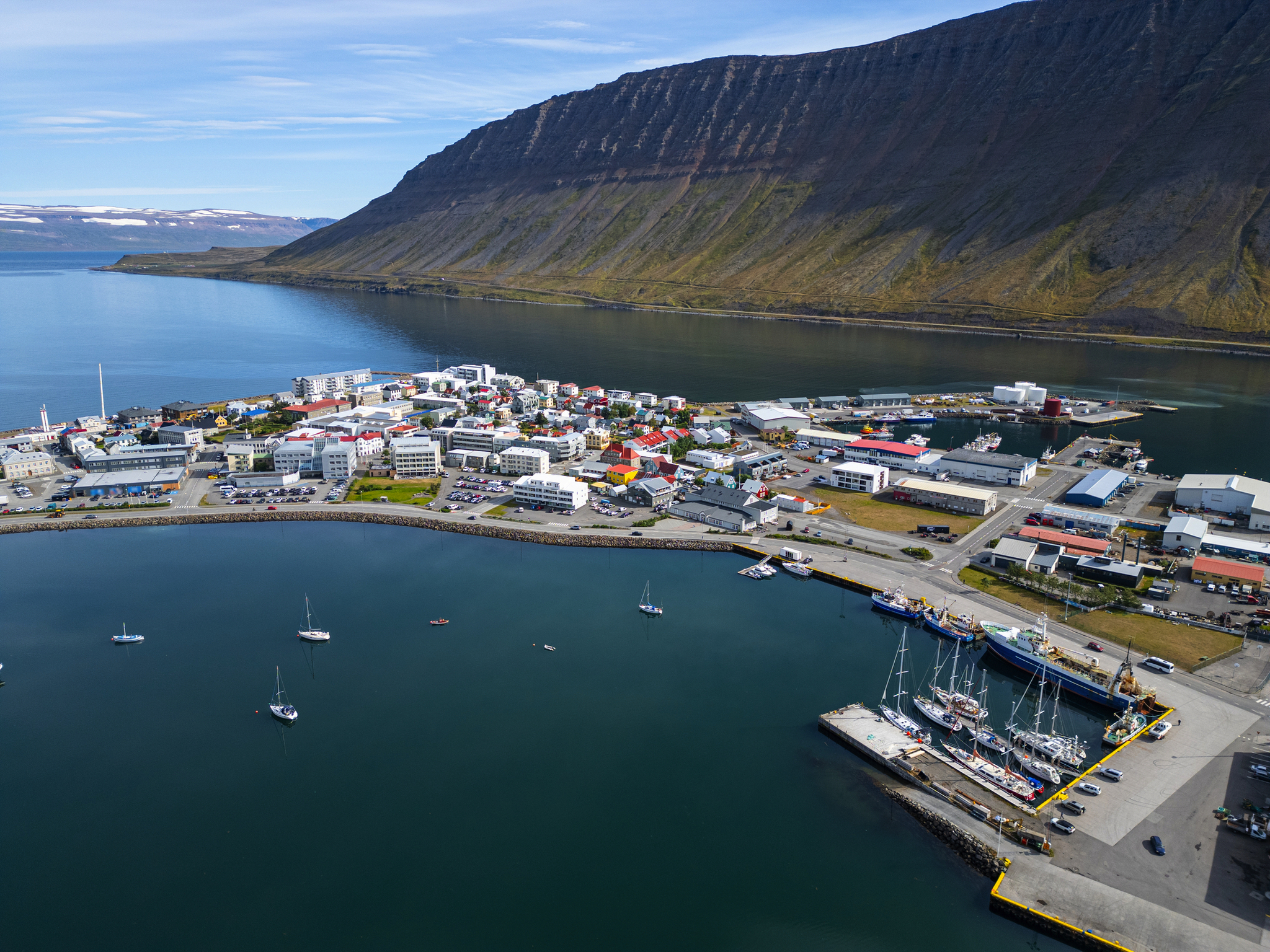 Küstenstadt mit Hafen, umgeben von Bergen und Meer.