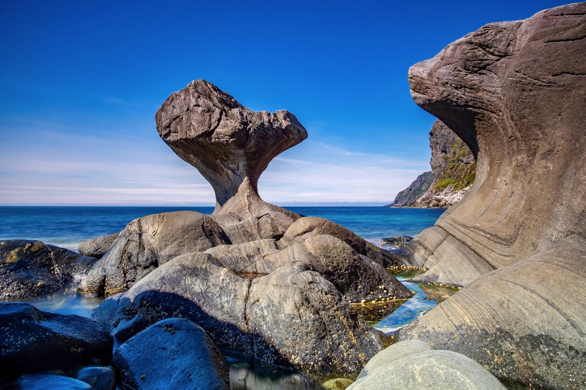 Felsformationen am Meer unter blauem Himmel.