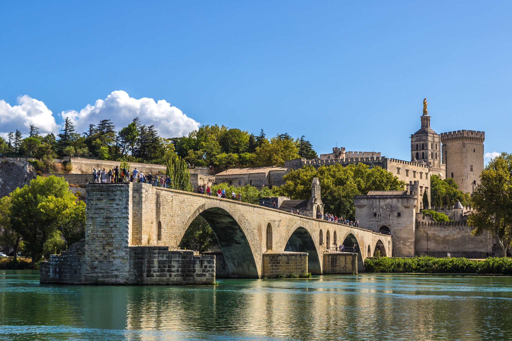 Steinbrücke über einen Fluss mit historischer Befestigungsanlage im Hintergrund.