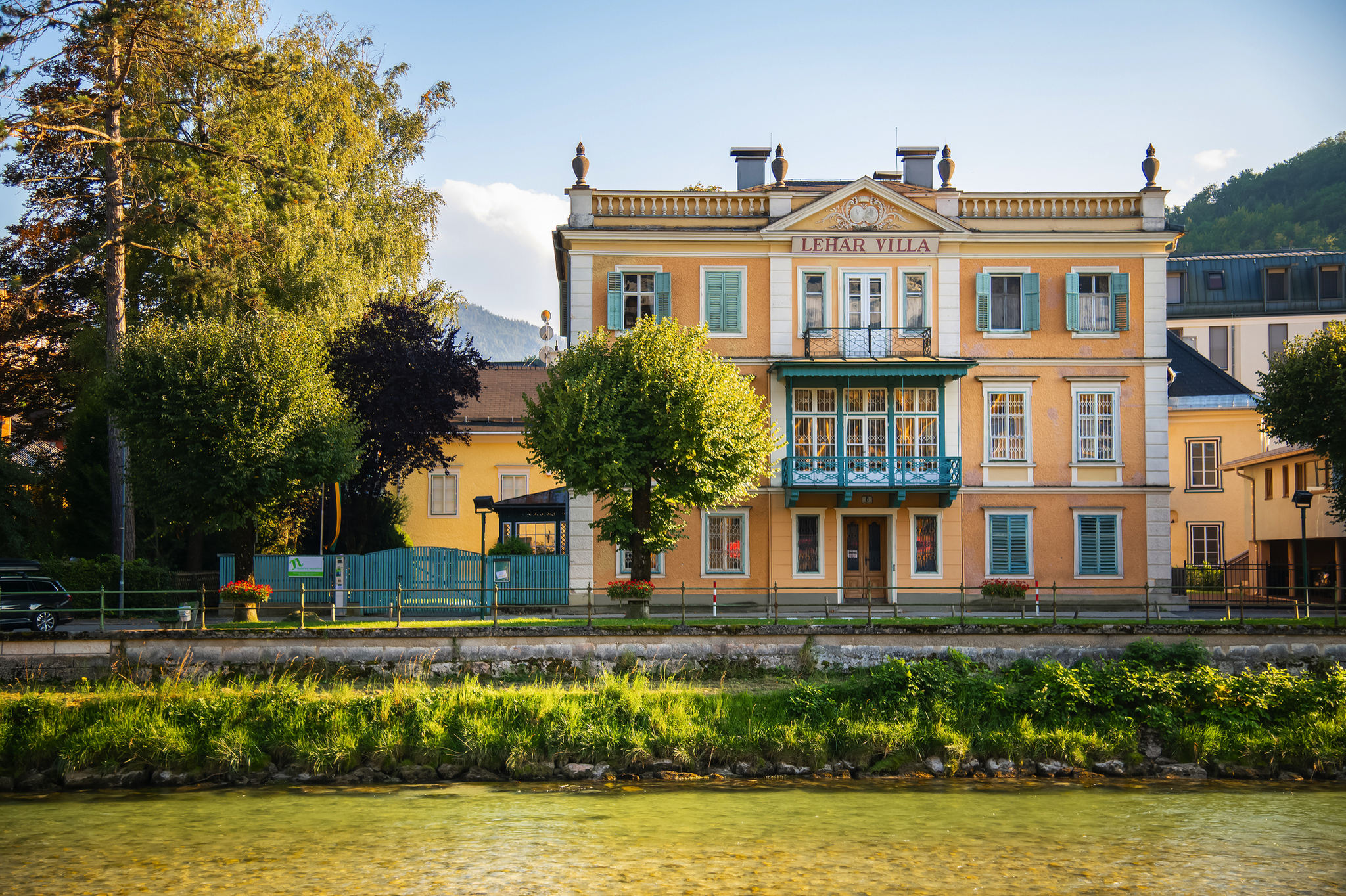 Lehar Villa in Bad Ischl im Salzkammergut, umgeben von Bäumen und einem Fluss im Vordergrund.
