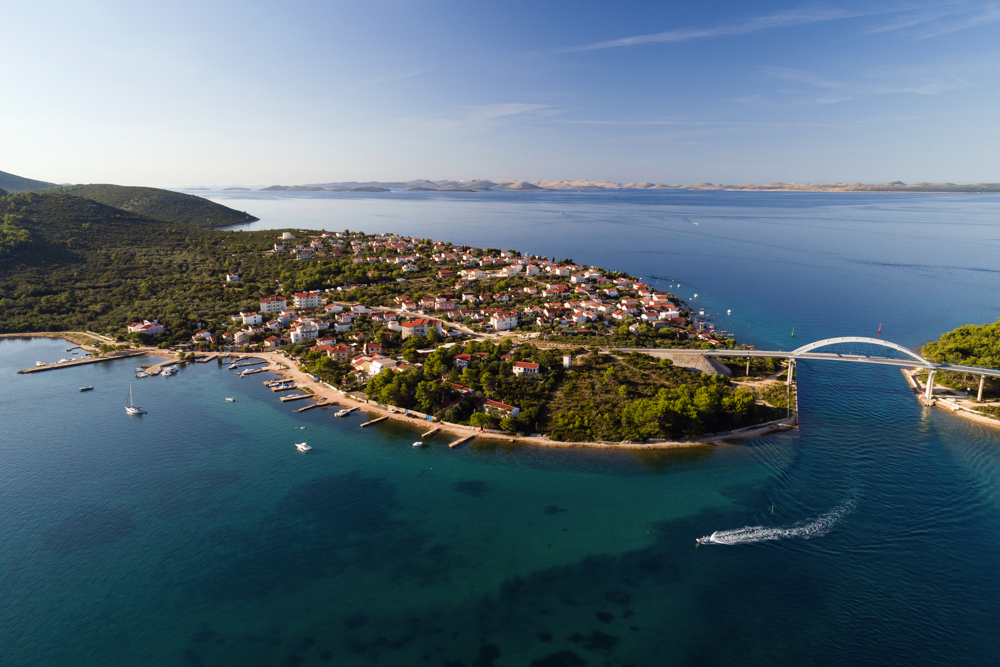 Luftaufnahme einer Küstenstadt mit Brücke und klarem blauen Wasser.