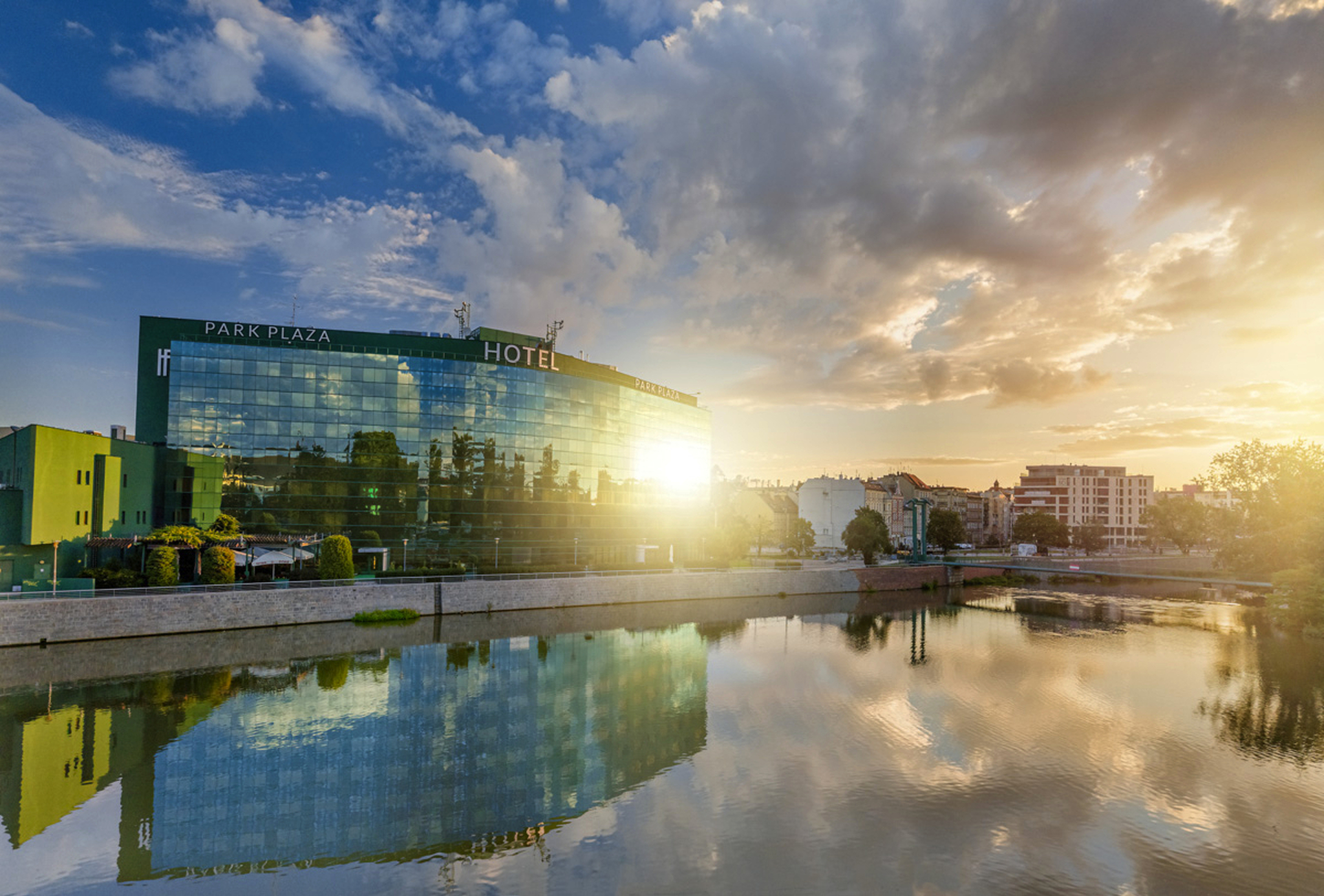 Hotelgebäude am Fluss bei Sonnenuntergang mit Spiegelung im Wasser.