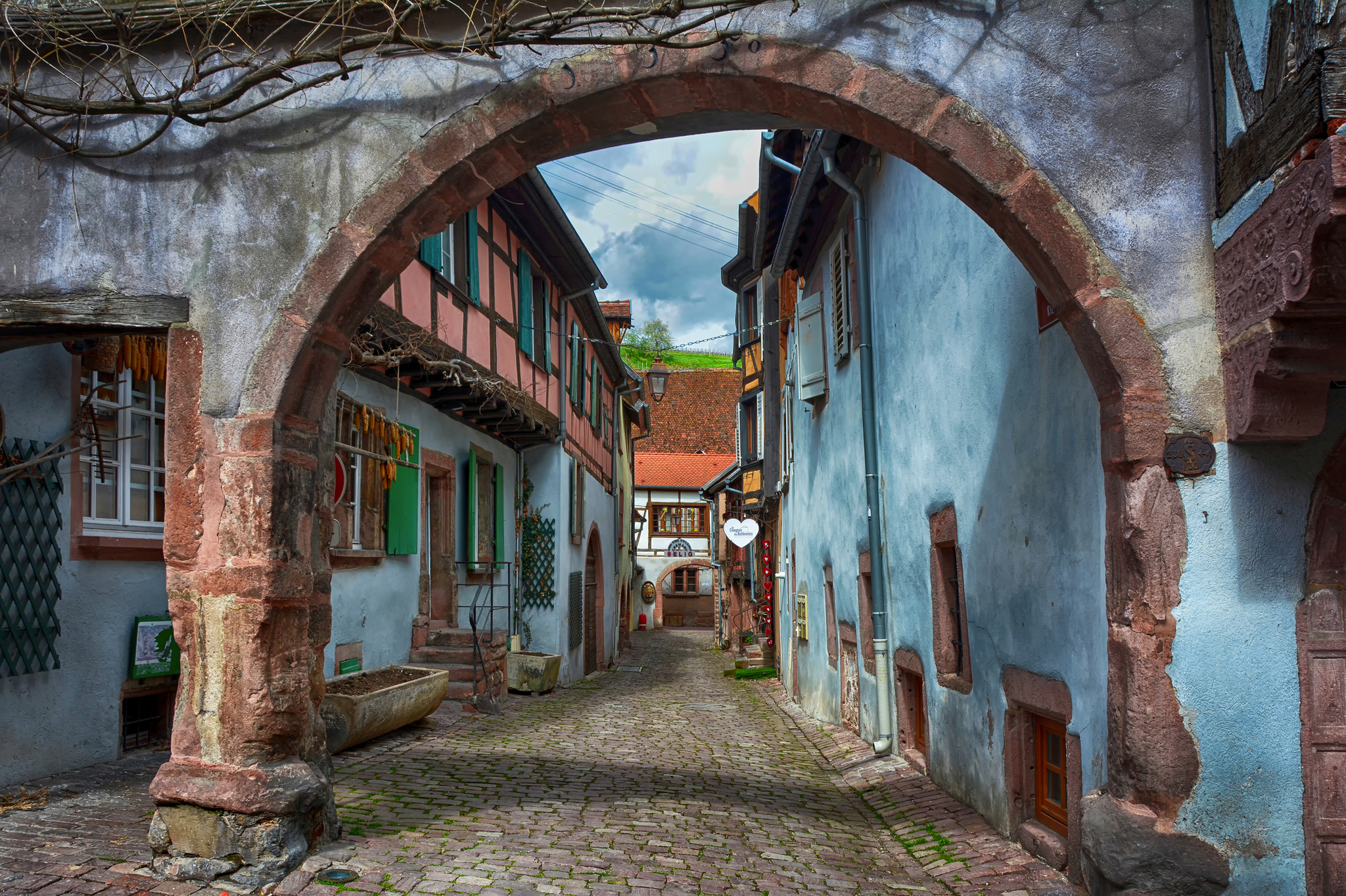 Gepflasterte Altstadtgasse mit historischen Fachwerkhäusern und steinernem Torbogen.