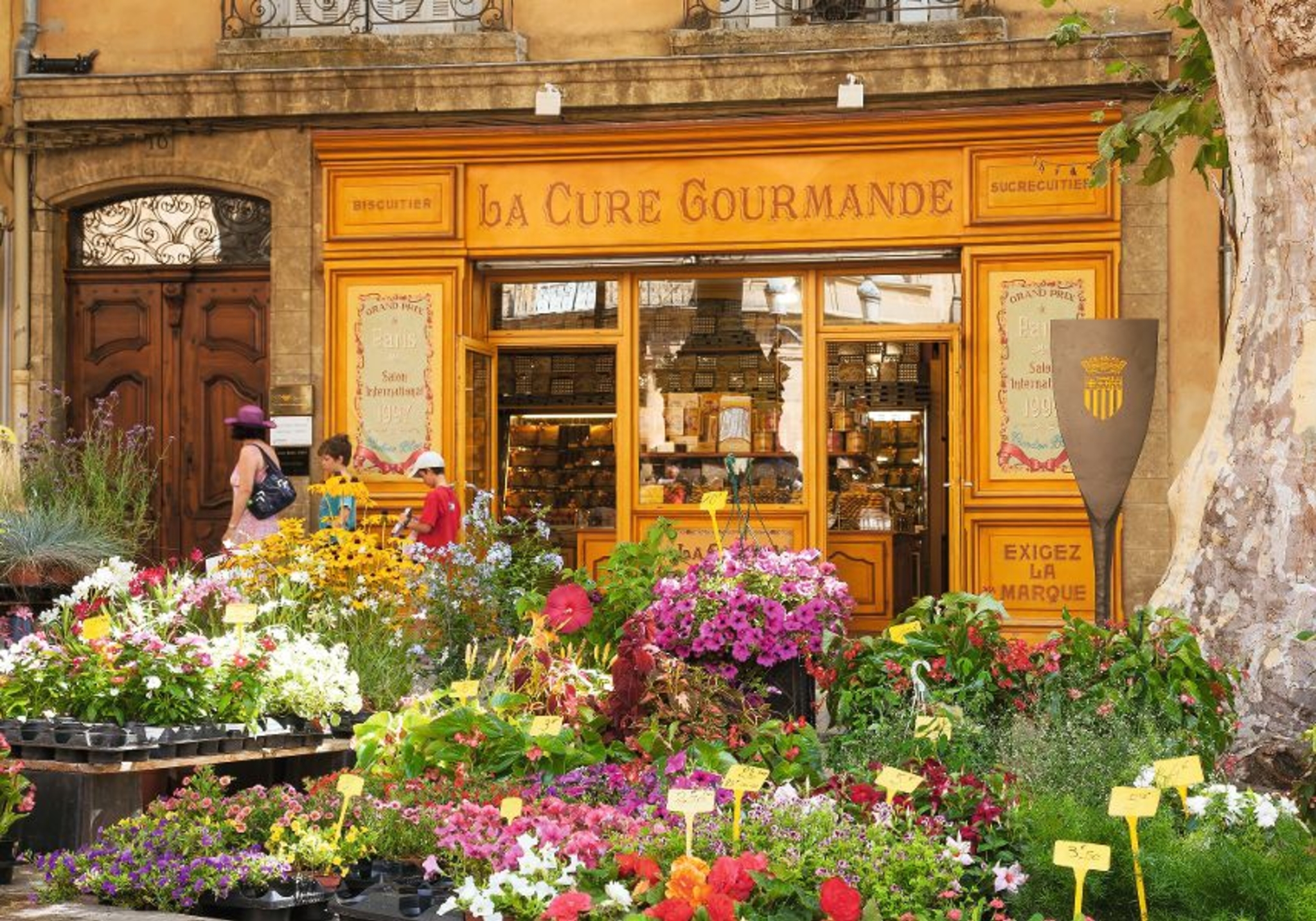 Historisches Geschäft mit gelber Fassade und blumengeschmücktem Eingang.