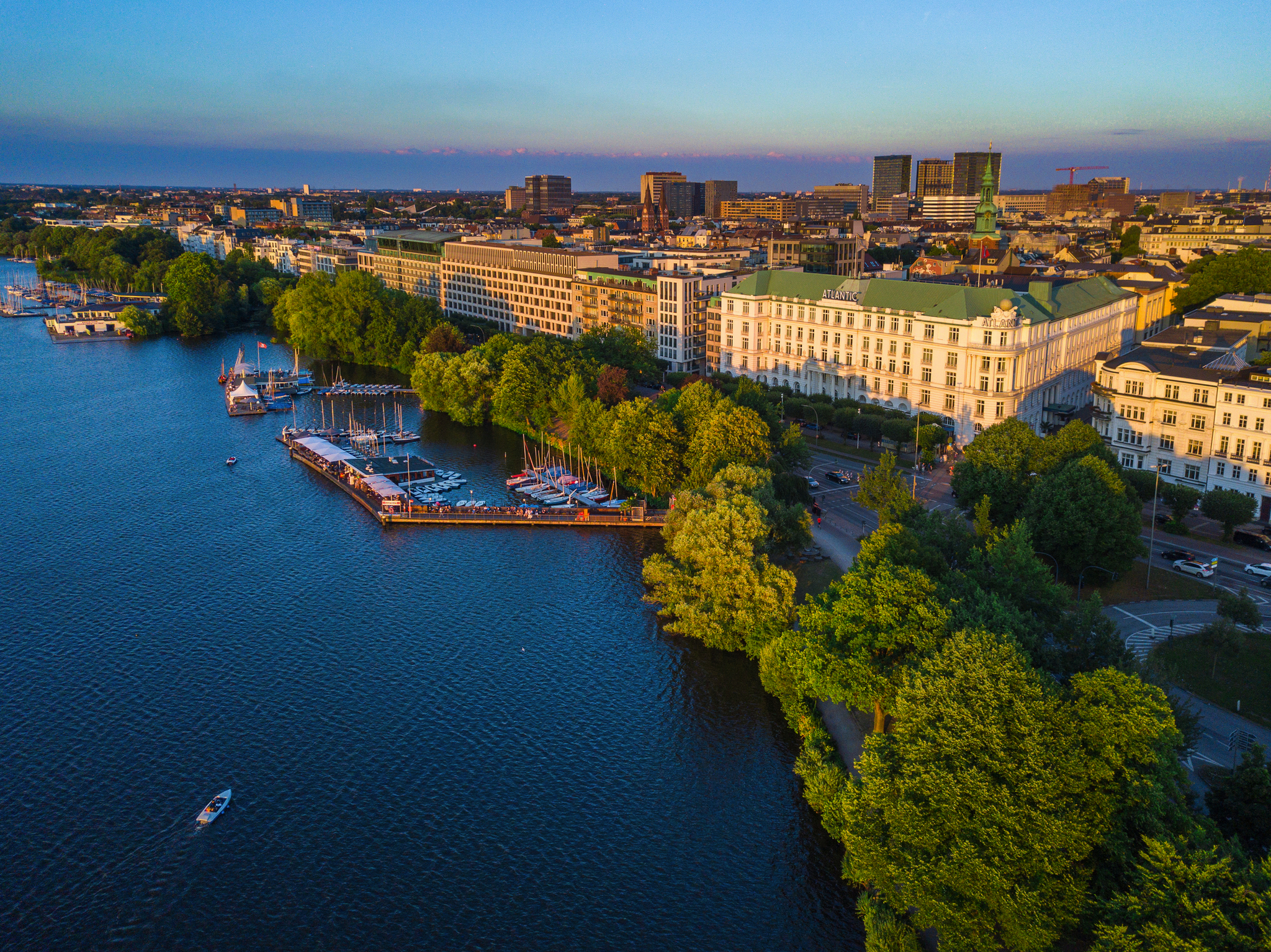 Luftbild einer Stadt am Wasser mit Booten und Gebäuden im Sonnenuntergang.