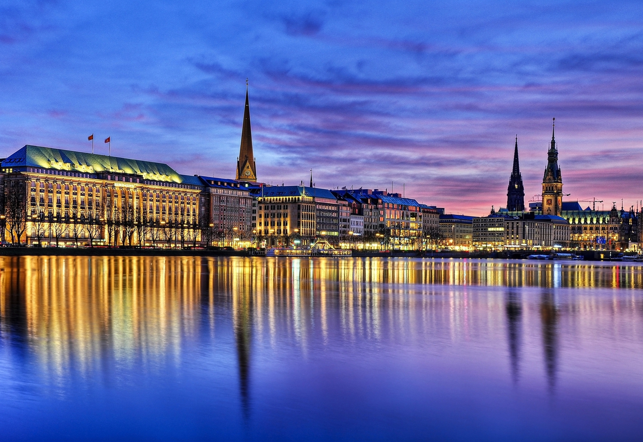 Stadtansicht von Hamburg bei Sonnenuntergang mit Spiegelung auf der Alster.