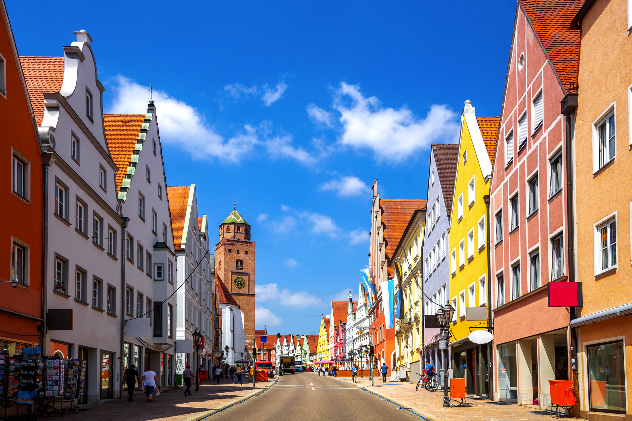 Bunte Fachwerkhäuser und Kirchturm in einer historischen europäischen Altstadt bei blauem Himmel.