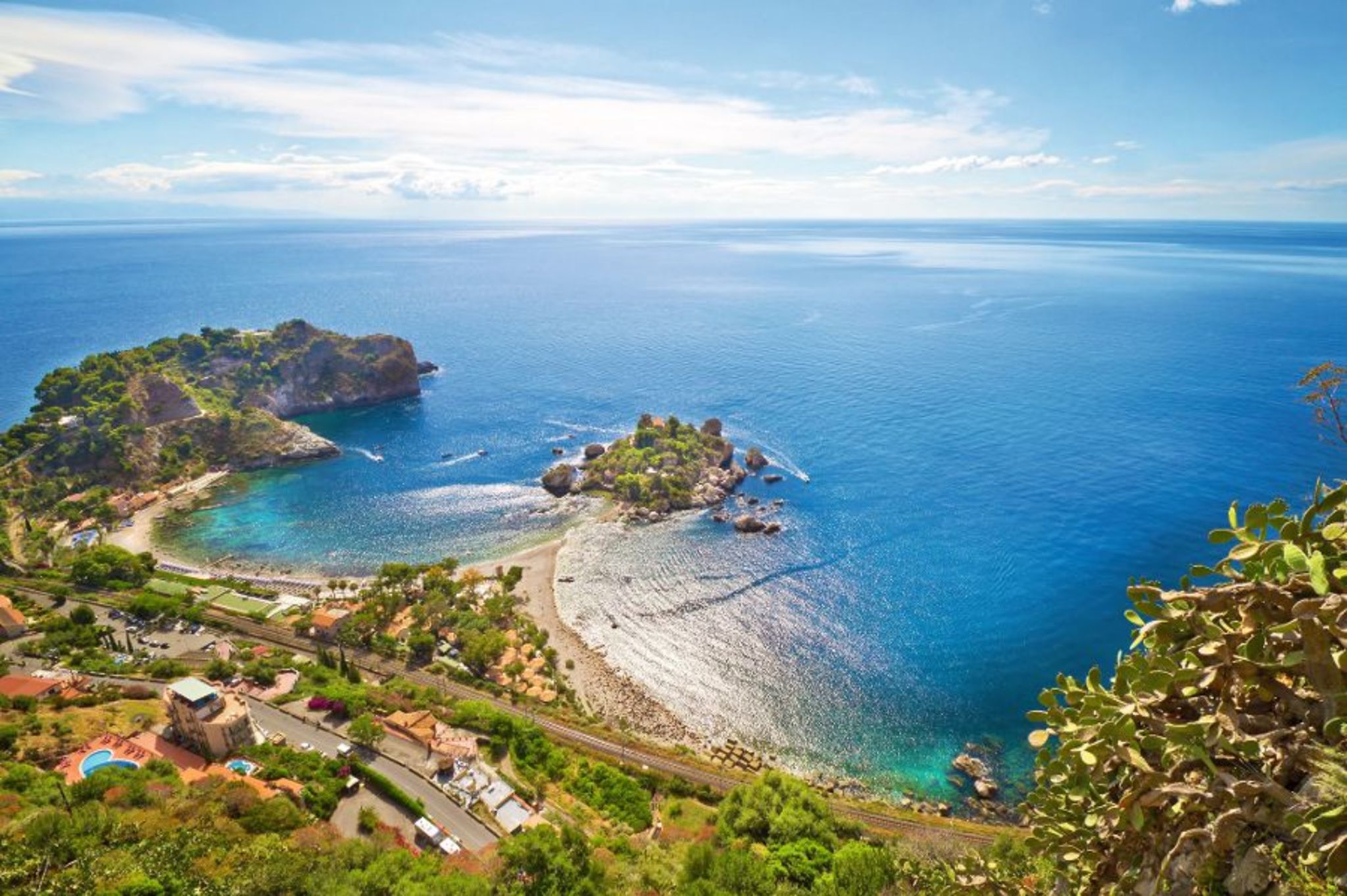 Blick auf Küste und Meer bei Taormina, Sizilien, mit blauem Himmel und Insel im Wasser.