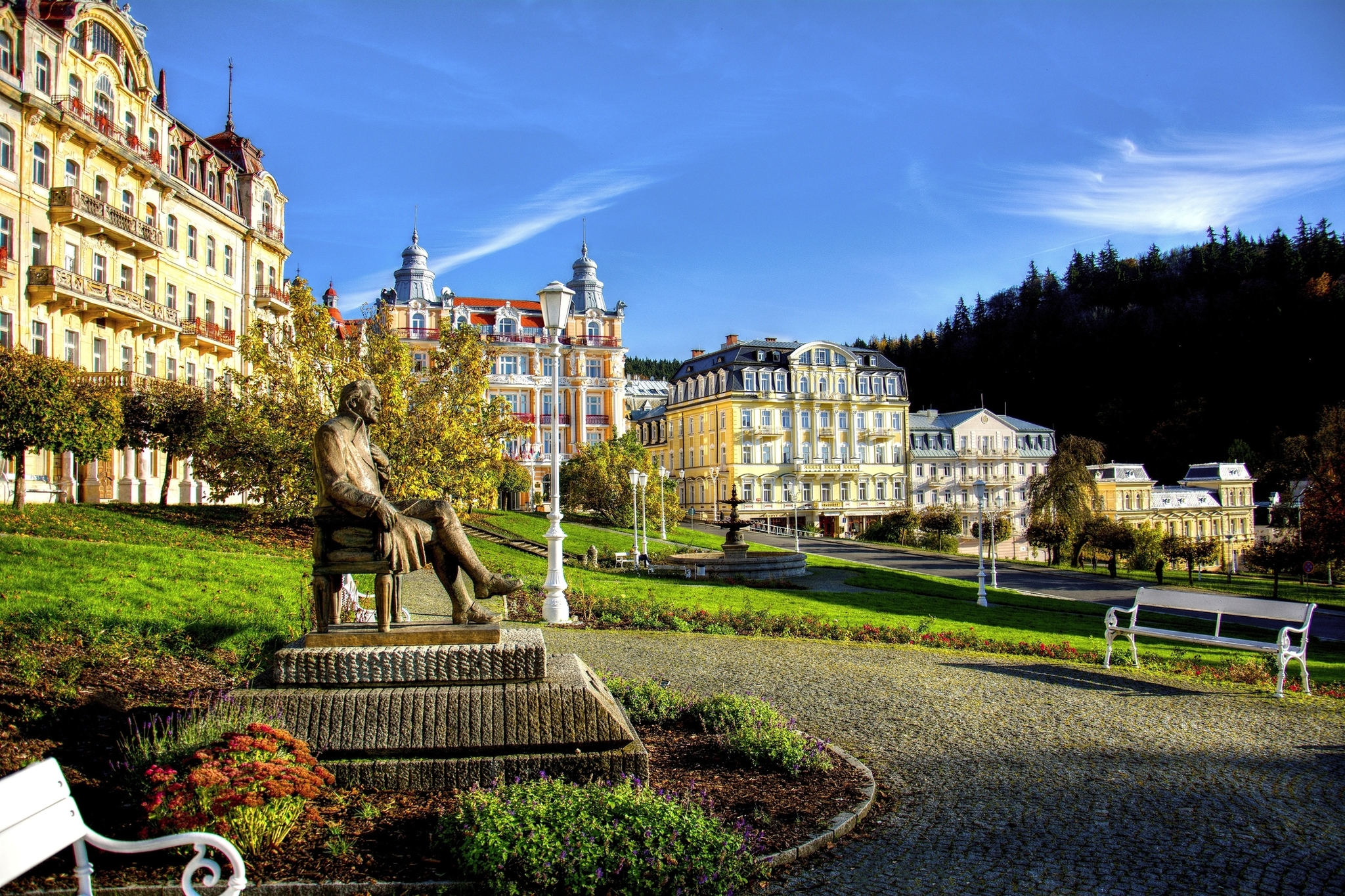 Statue in einem gepflegten Park, umgeben von historischen Gebäuden und Bäumen.