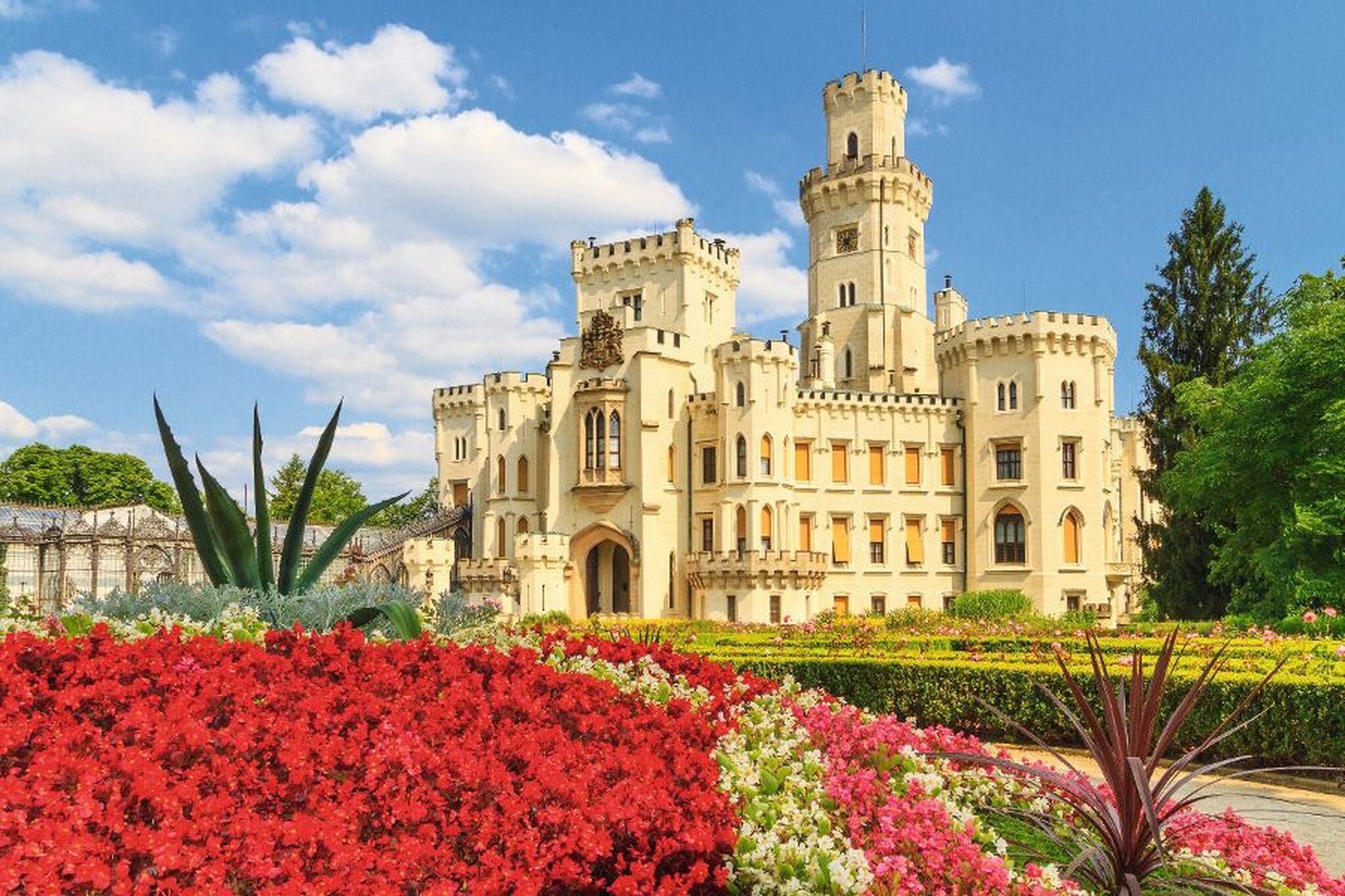 Historisches Schloss mit Garten und Blumen im Vordergrund.
