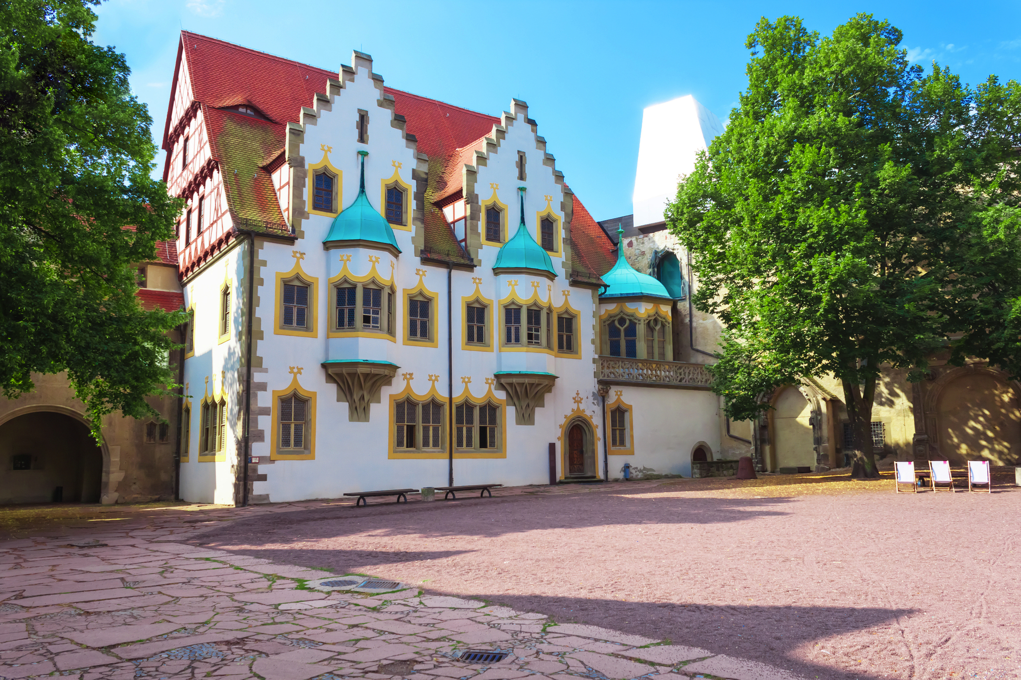 Historisches Gebäude mit Zinnen und roten Dächern in sonniger Umgebung.