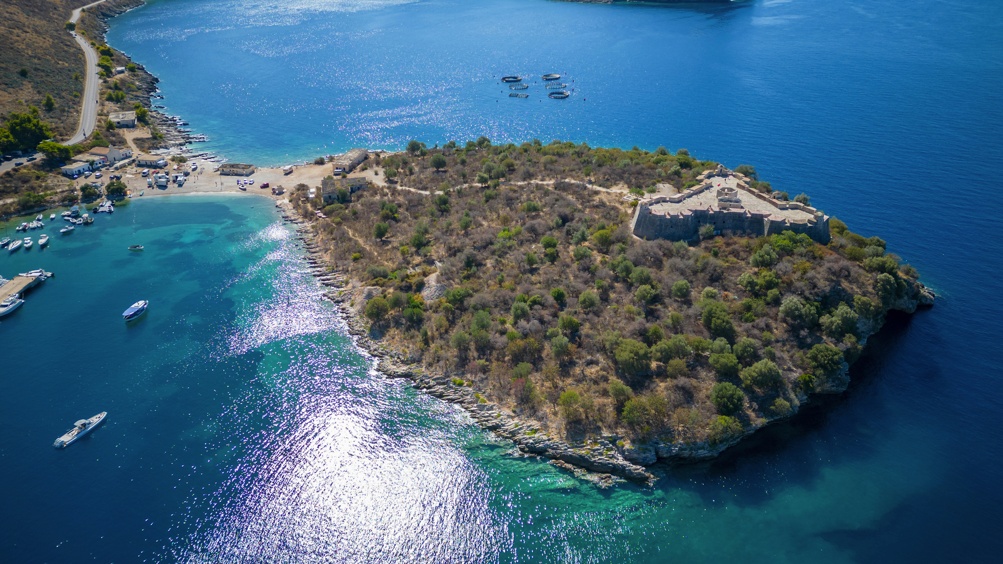 Luftaufnahme einer bewachsenen Halbinsel im blauen Meer mit kleinen Booten.