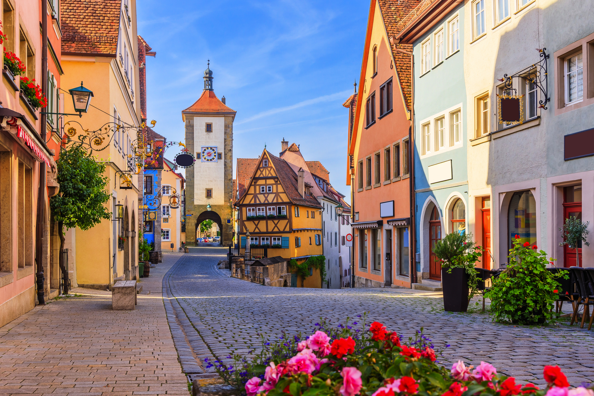 Malerische Altstadtstraße mit bunten Fachwerkhäusern und historischer Torbogen.