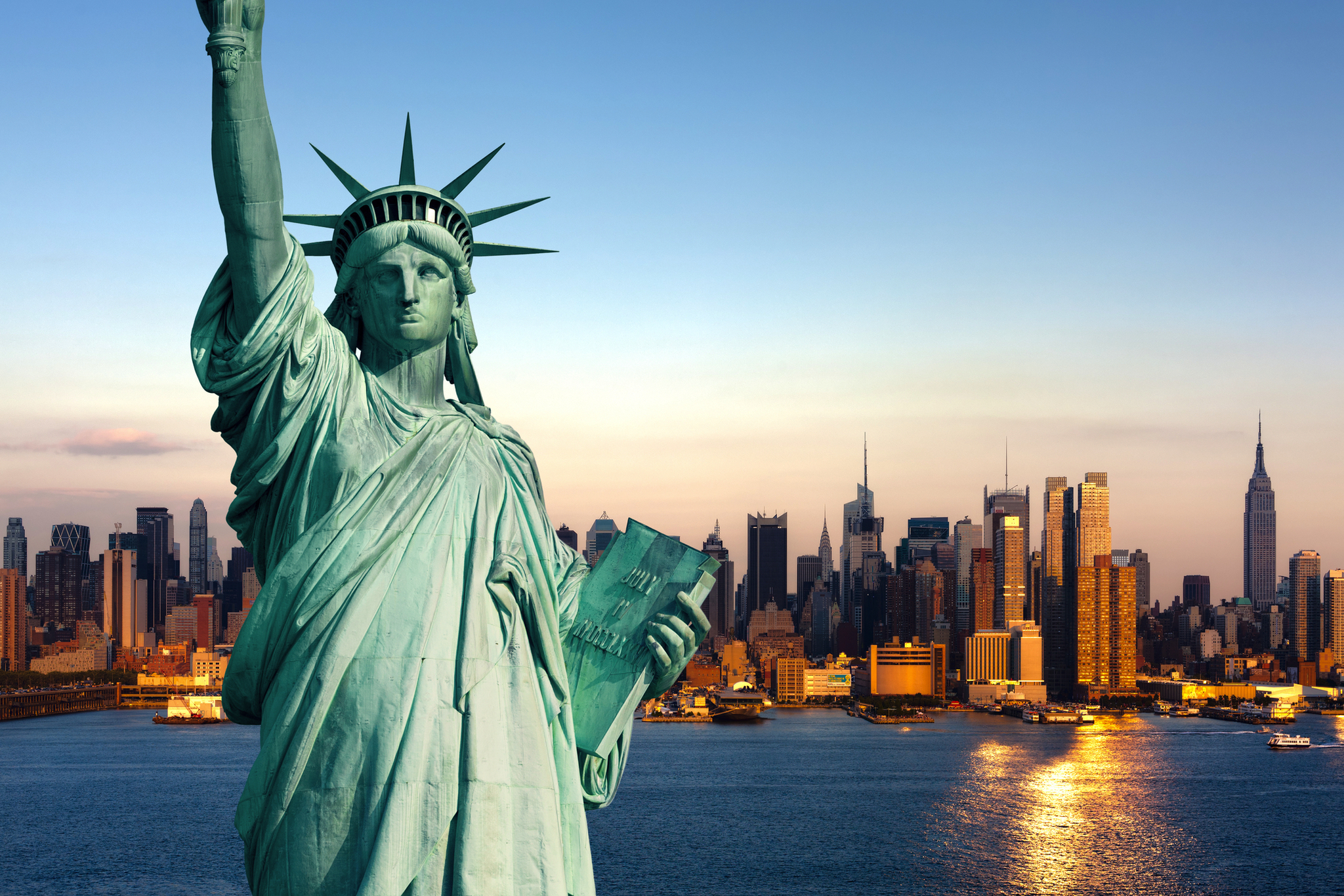 Freiheitsstatue vor der Skyline von Manhattan in New York City bei Sonnenuntergang.