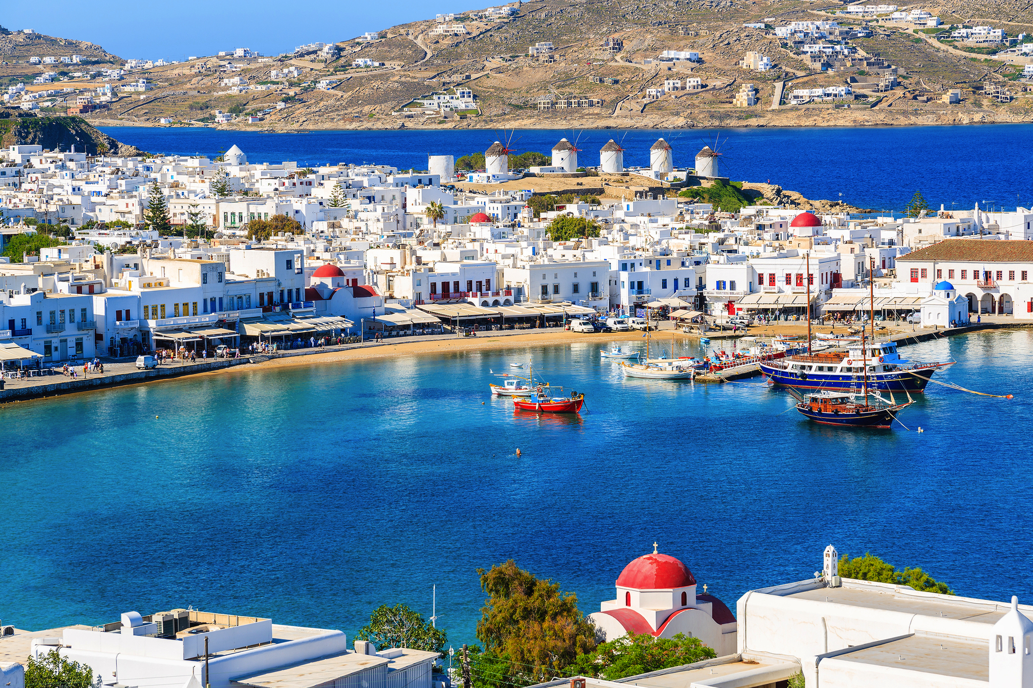 Mykonos mit Blick auf den Hafen, weiße Häuser und Windmühlen im Hintergrund.
