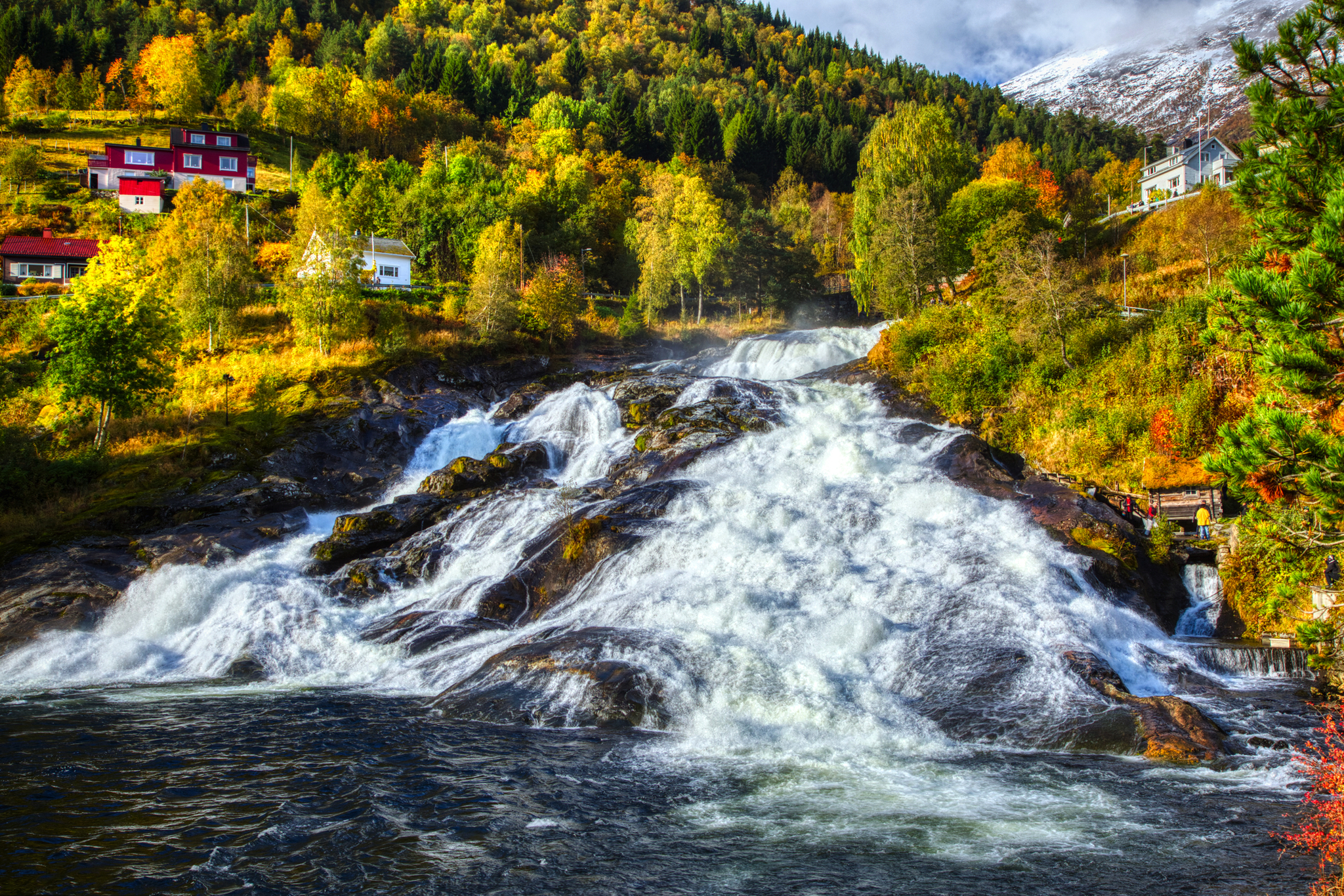 Wasserfälle in Hellesylt im Herbst, umgeben von buntem Laub und kleinen Häusern.