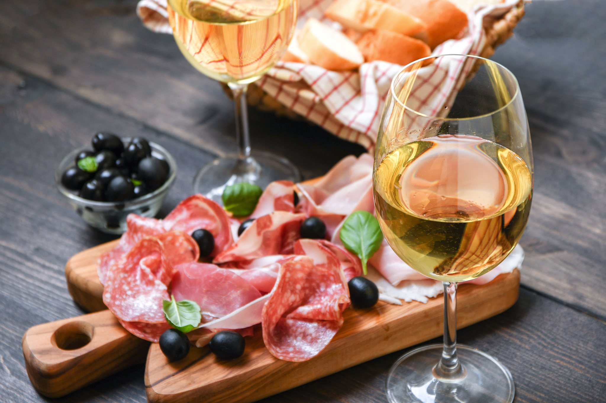 Weißwein, Aufschnitt und Oliven auf Holzbrett.