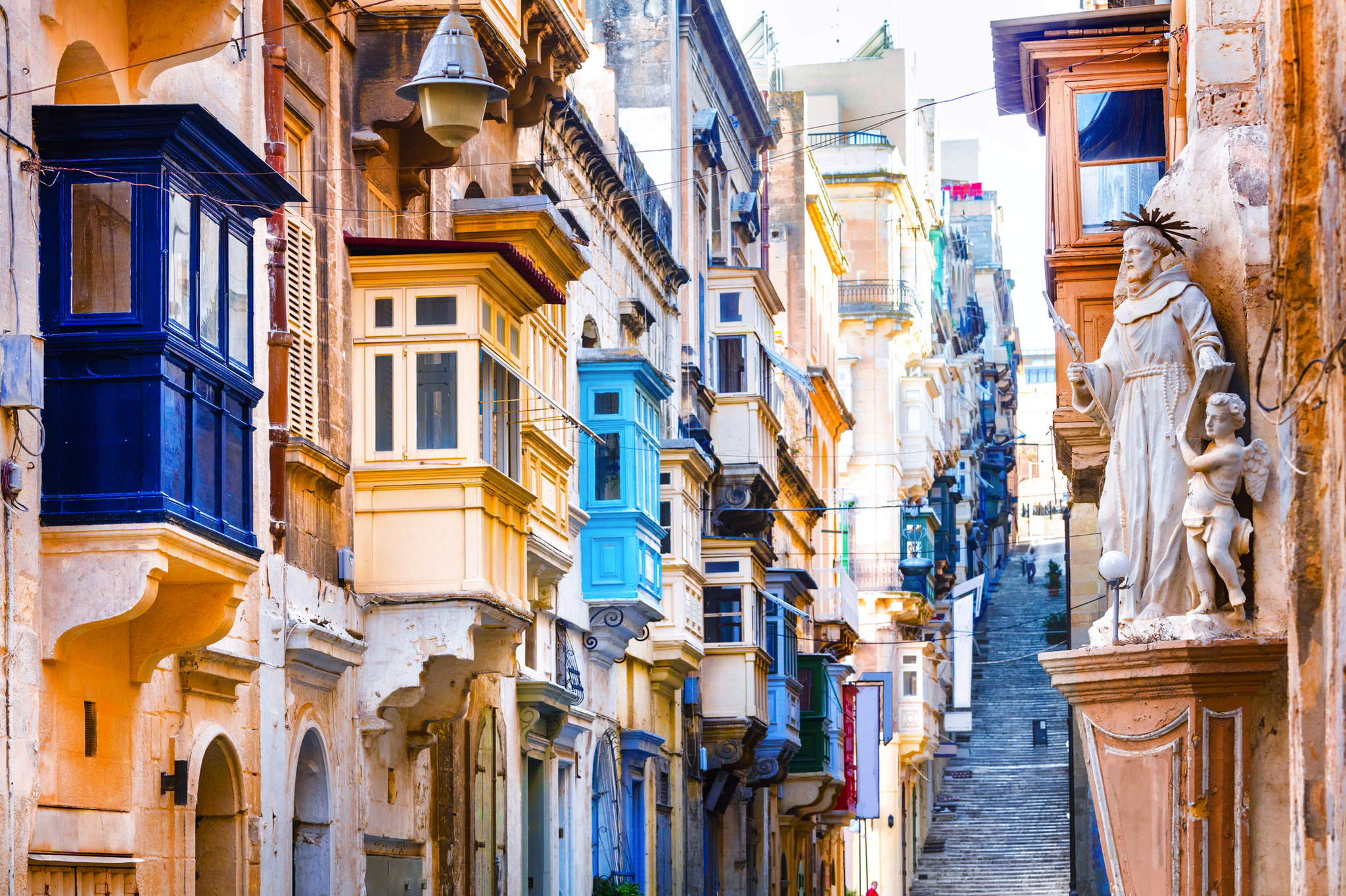 Bunte Balkone an einer engen, steilen Gasse in einer historischen Stadt.