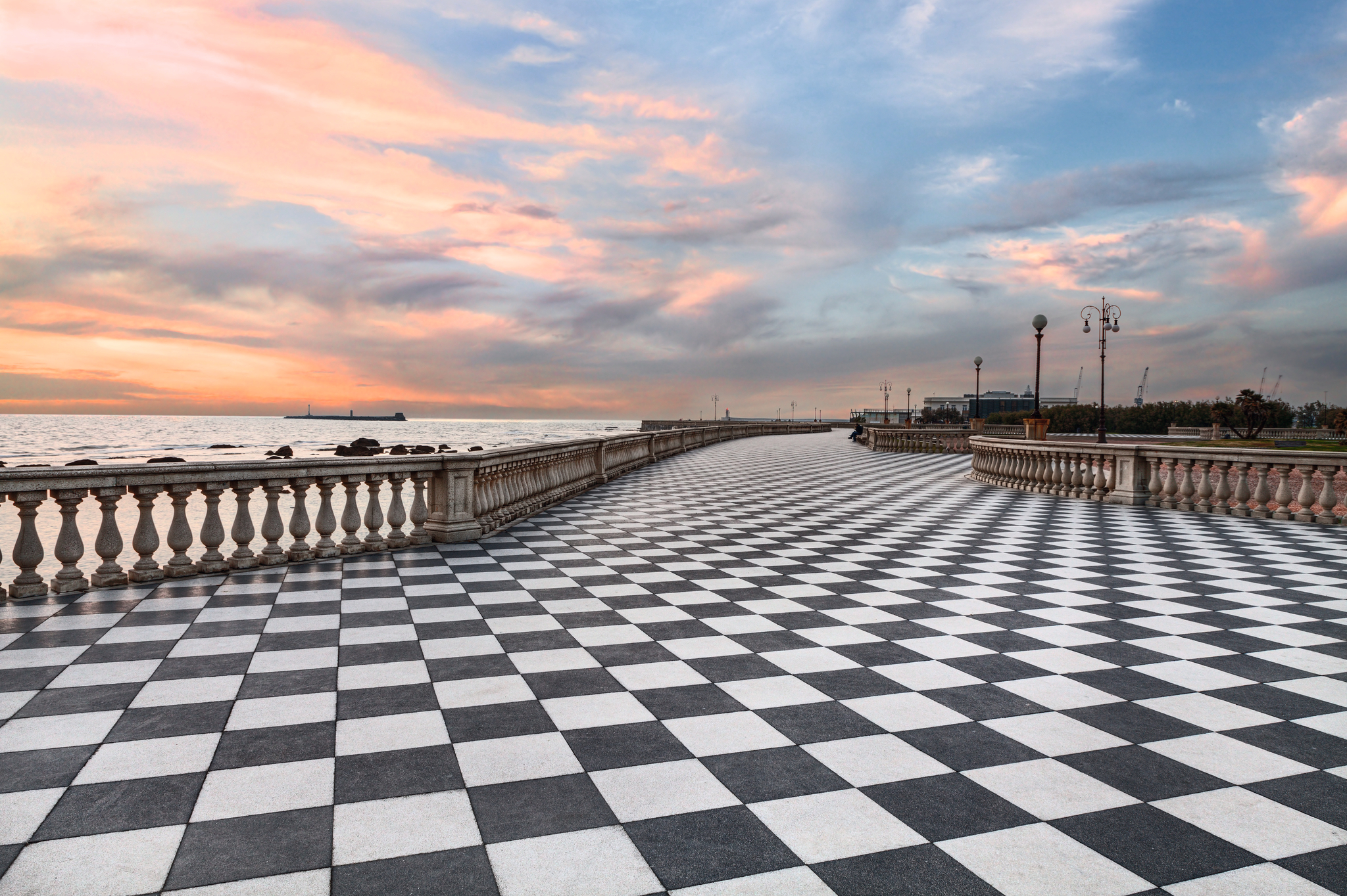Promenade mit Schachbrettmusterboden bei Sonnenuntergang am Meer in Livorno, Italien.