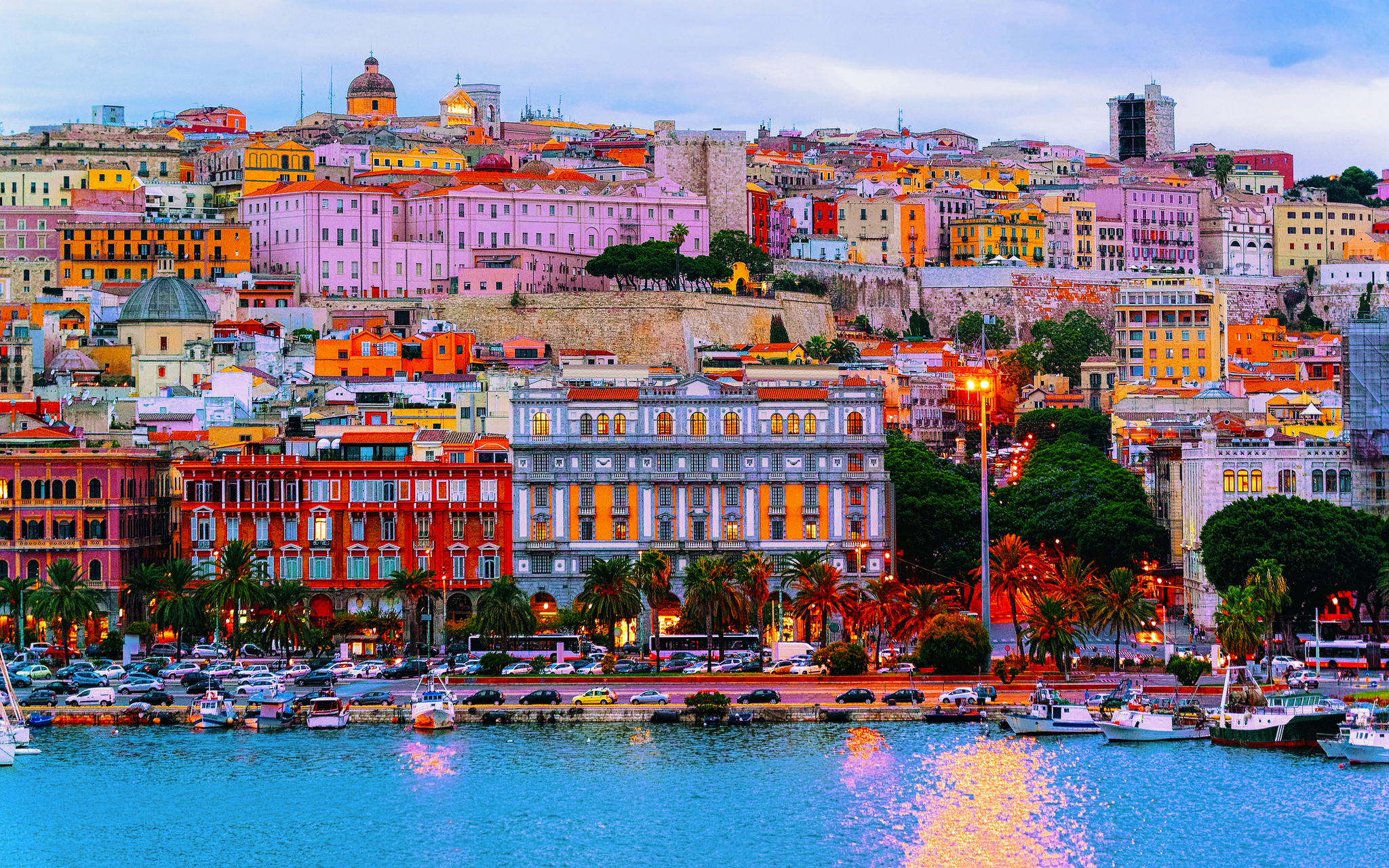 Hafen von Cagliari auf Sardinien mit historischen Gebäuden und Booten im Vordergrund.