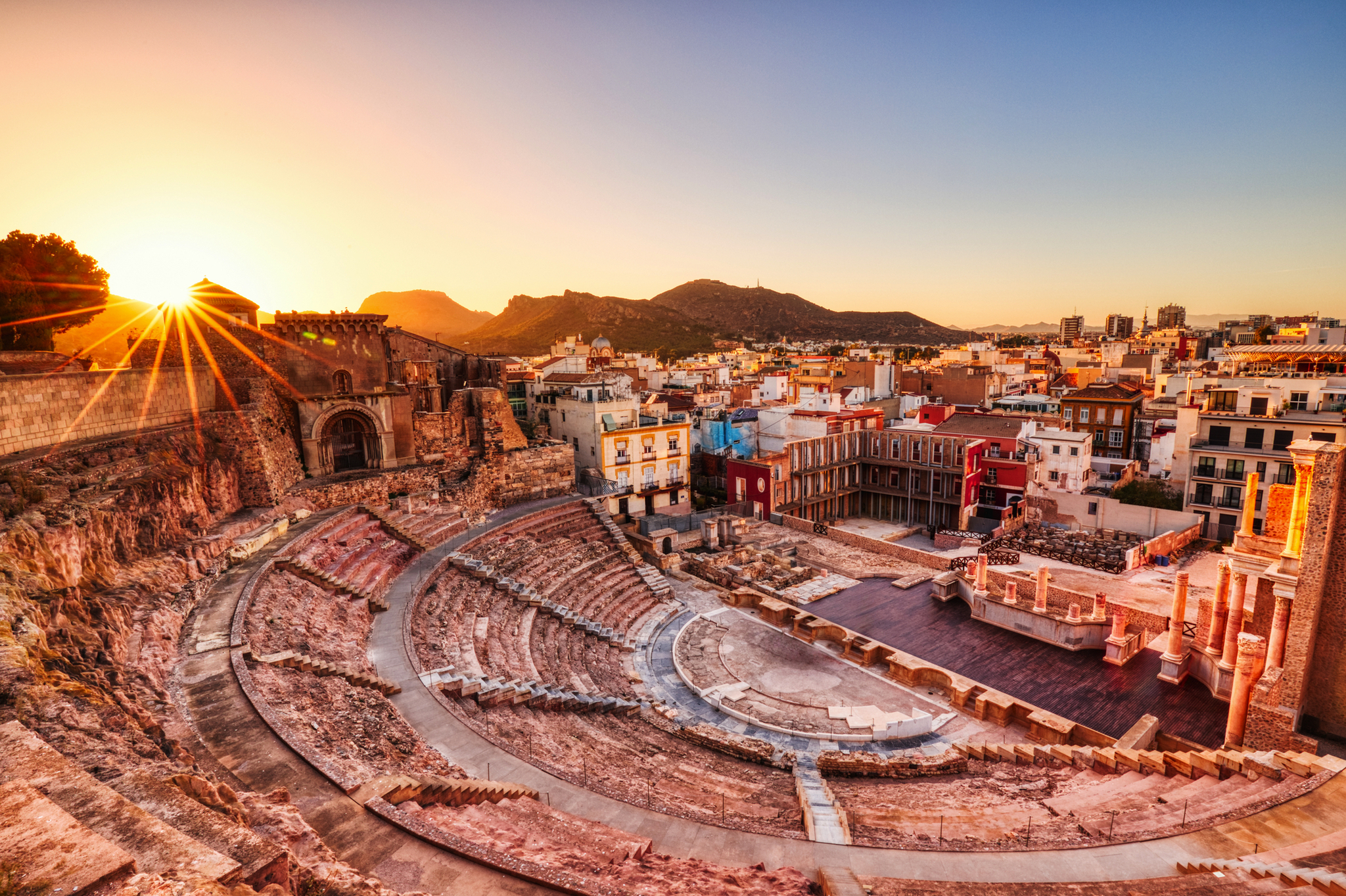 Römisches Amphitheater bei Sonnenuntergang mit Stadtansicht im Hintergrund