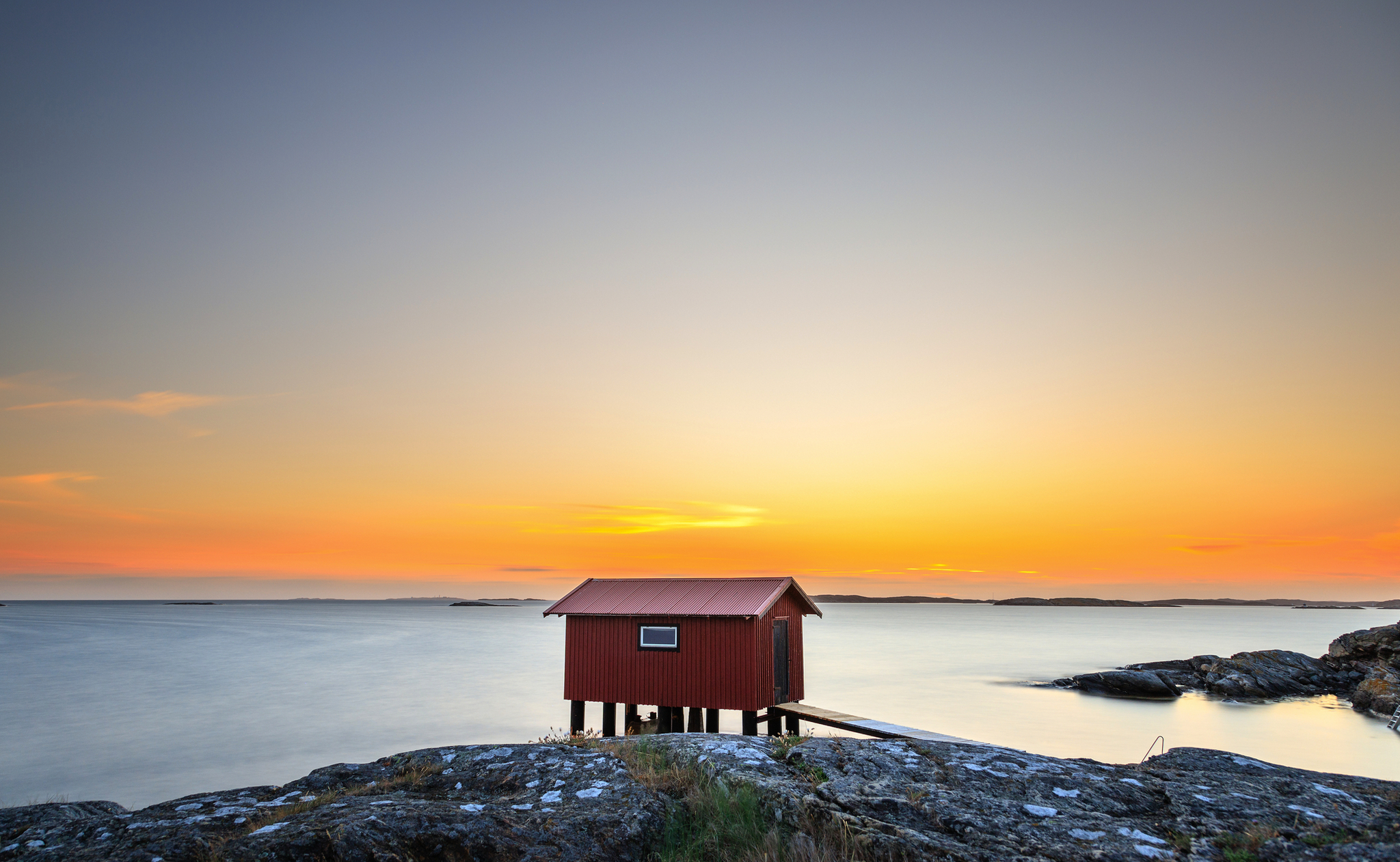 Holzhütte auf Felsen vor Sonnenuntergang am Meer