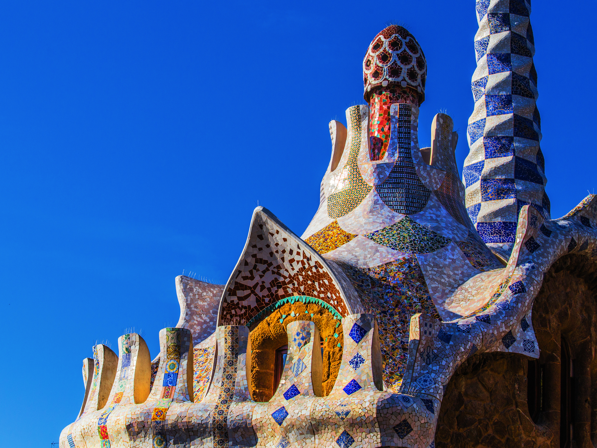 Park Güell in Barcelona zeigt farbenfrohe und kunstvolle Gebäude, entworfen von Antoni Gaudí, die ein Wahrzeichen der Stadt und eine beliebte Sehenswürdigkeit in Katalonien sind.