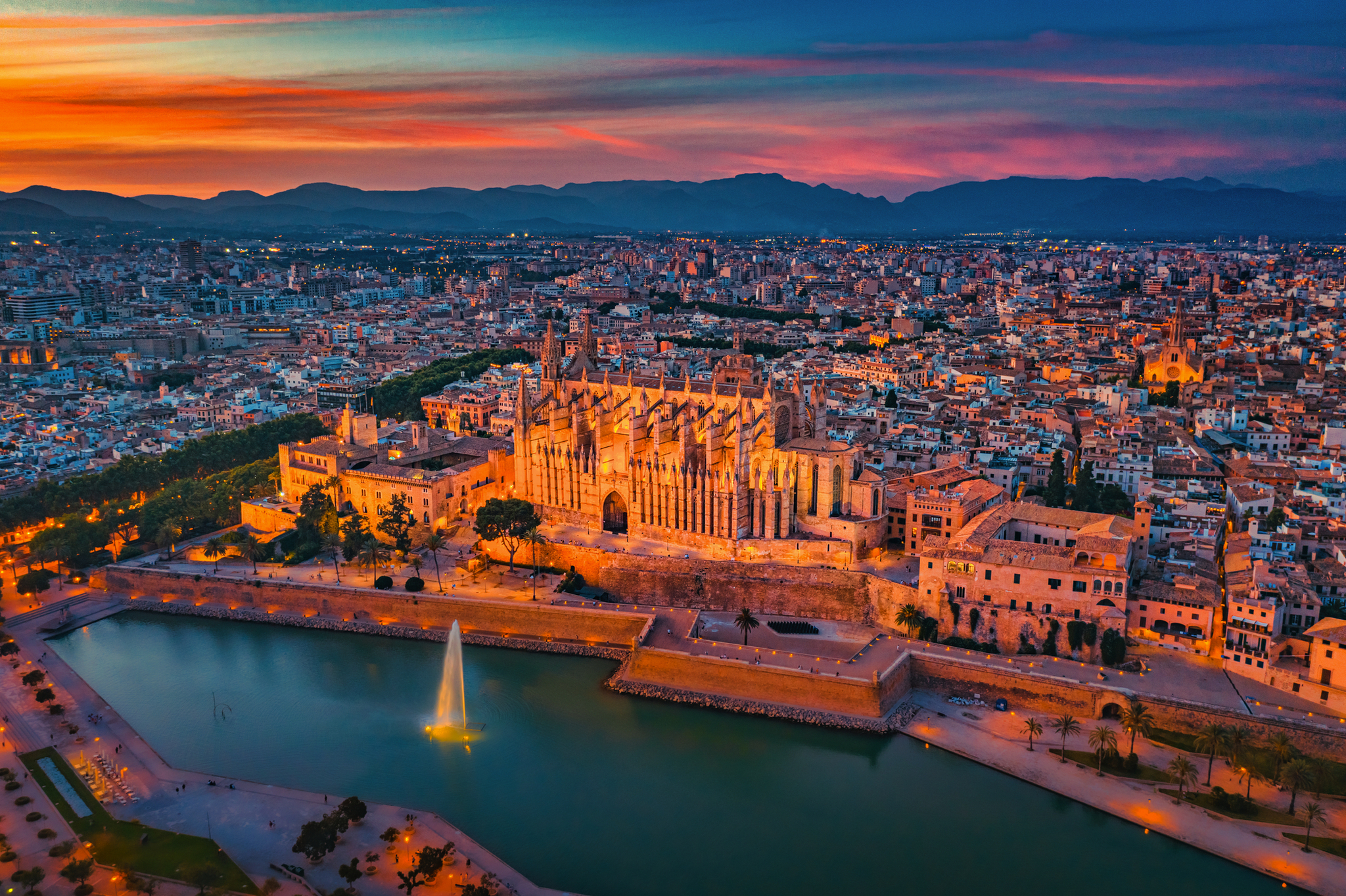 Luftaufnahme der Kathedrale von Palma bei Sonnenuntergang, Mallorca, mit Stadt und Wasser.