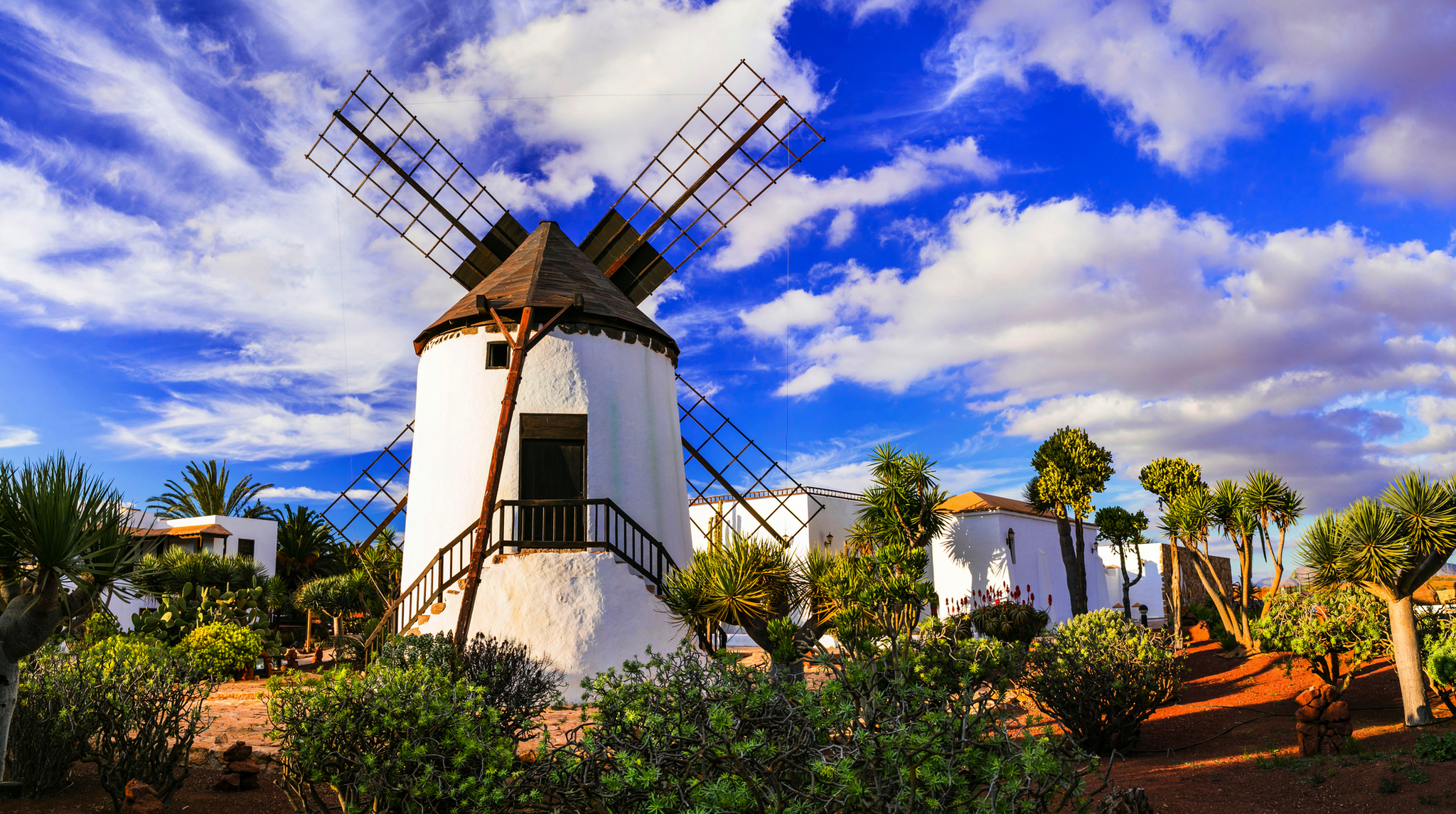 Traditionelle Windmühle in einer Landschaft mit blauem Himmel und Wolken.