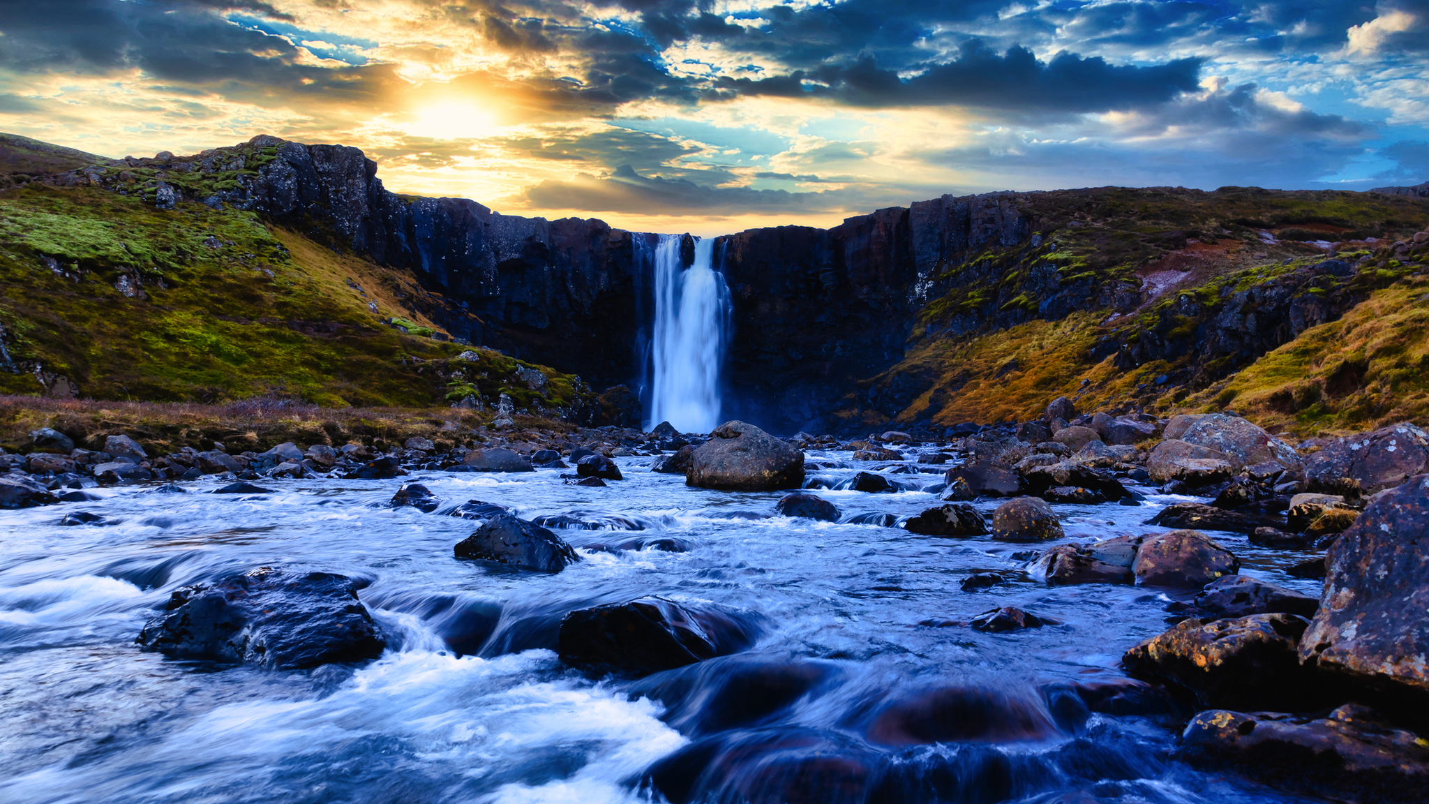 Wasserfall in einer felsigen Landschaft bei Sonnenuntergang.