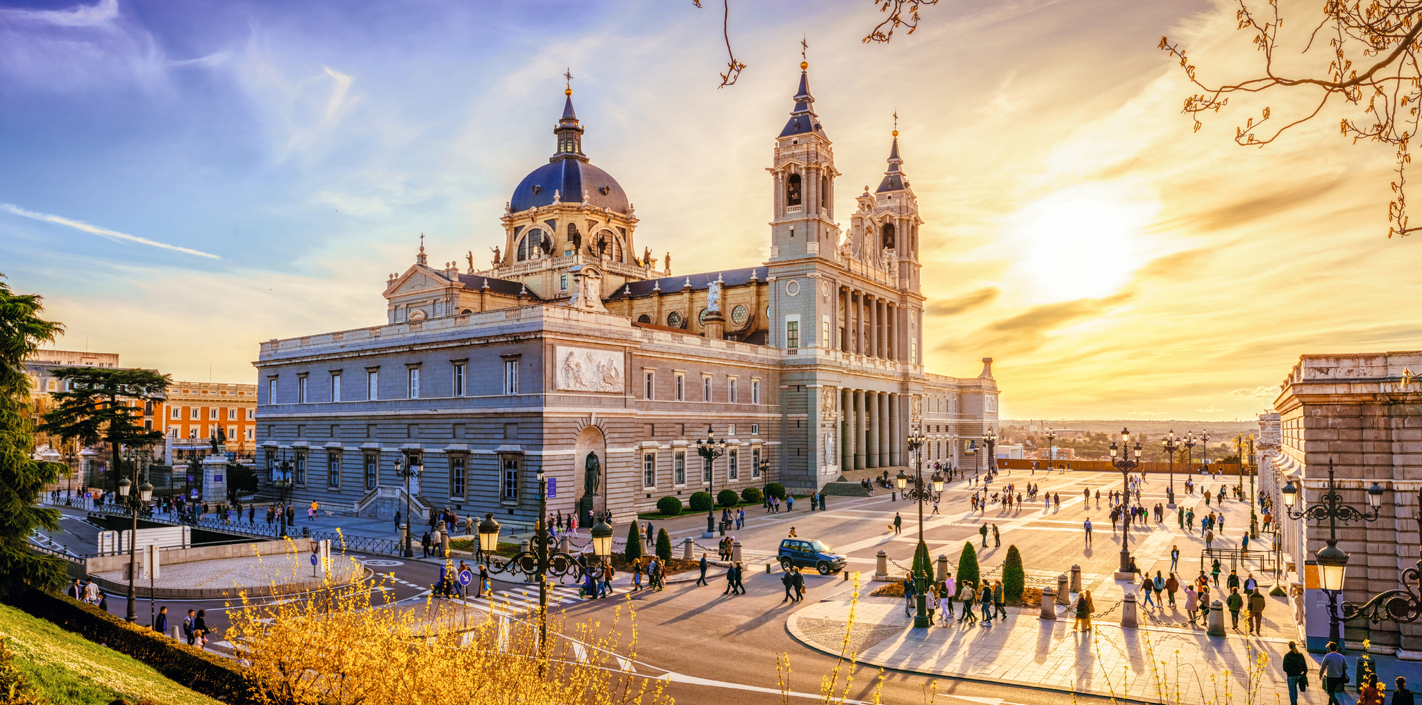 Kathedrale Almudena in Madrid bei Sonnenuntergang, mit Menschen auf dem Platz davor.
