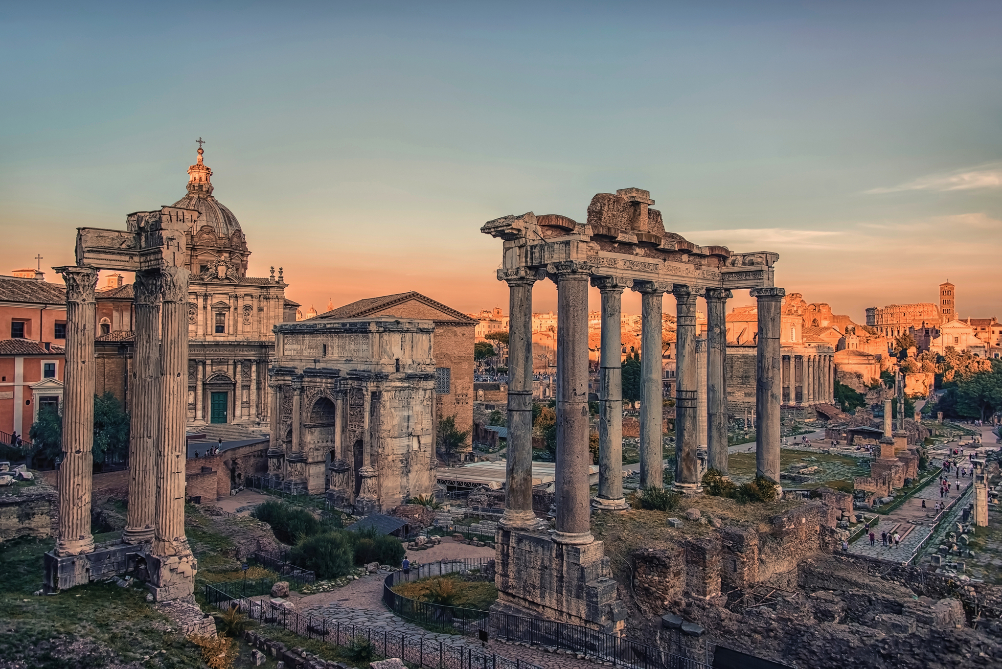 Forum Romanum in Rom bei Sonnenuntergang mit antiken Ruinen und Säulen im Vordergrund.