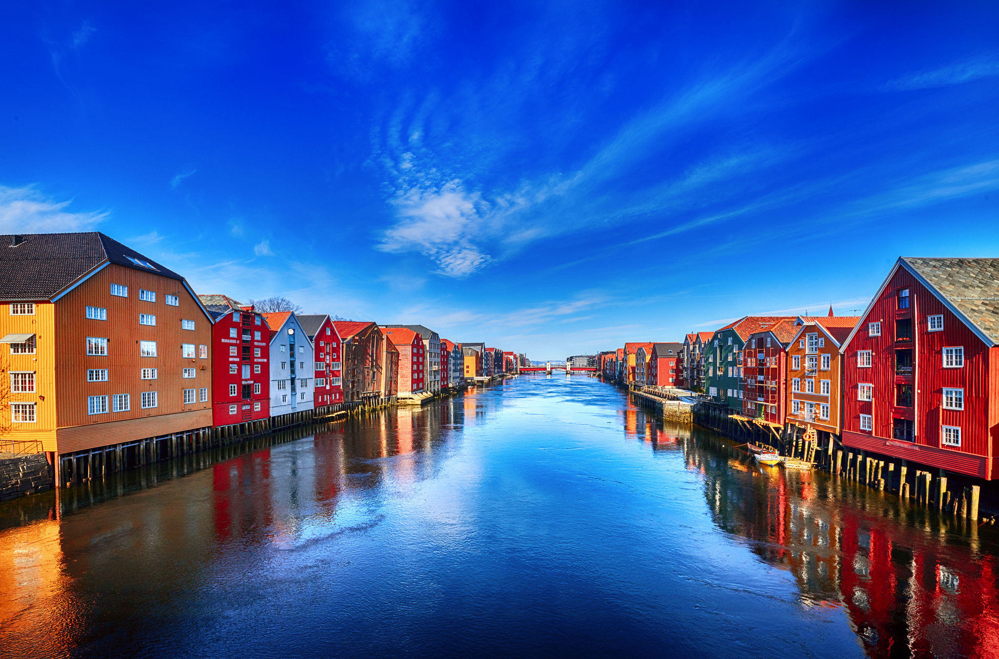 Bunte Häuser entlang des Trondheimer Fjords in Trondheim, Norwegen, unter klarem blauem Himmel.