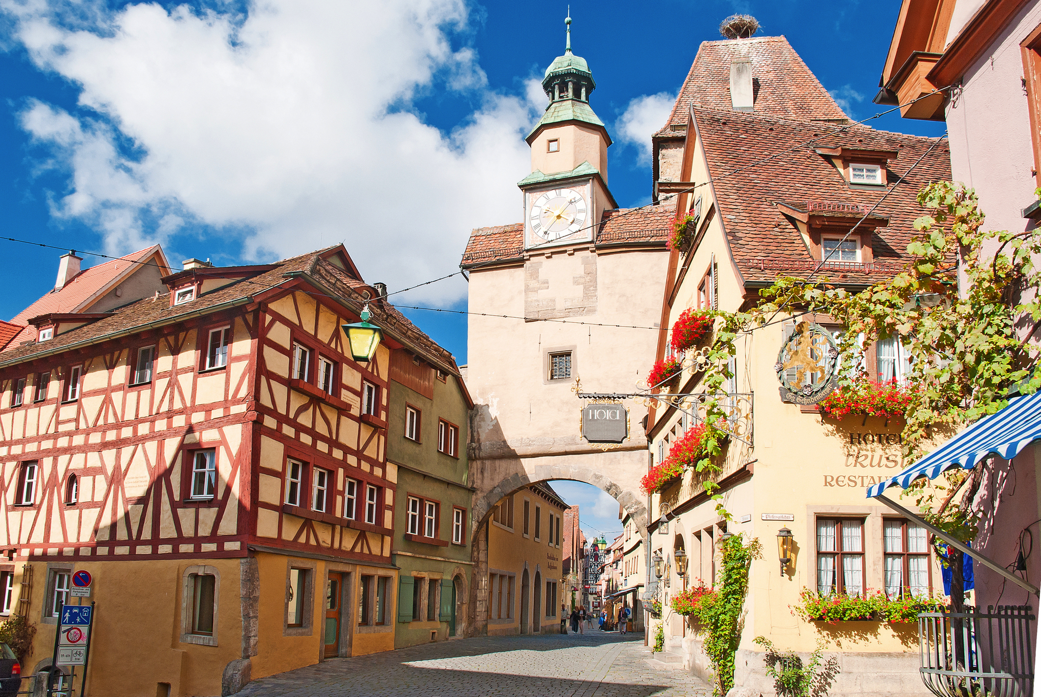 Historisches Stadttor und Fachwerkhäuser bei sonnigem Wetter.