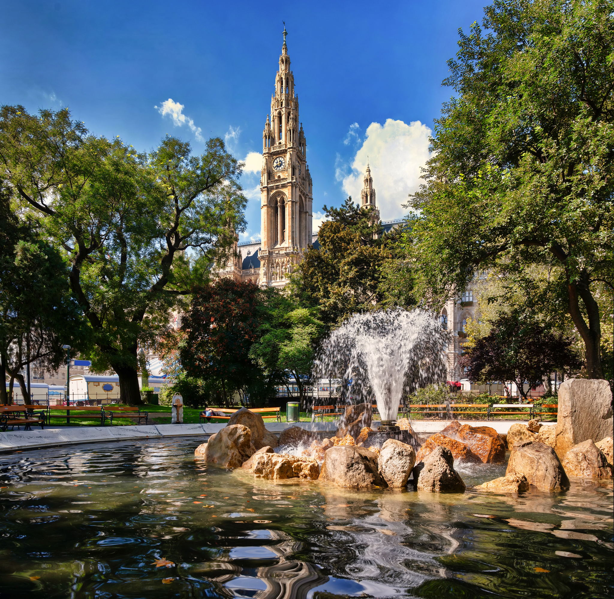 Rathauspark in Wien mit Brunnen und Blick auf die gotische Architektur des Rathauses.
