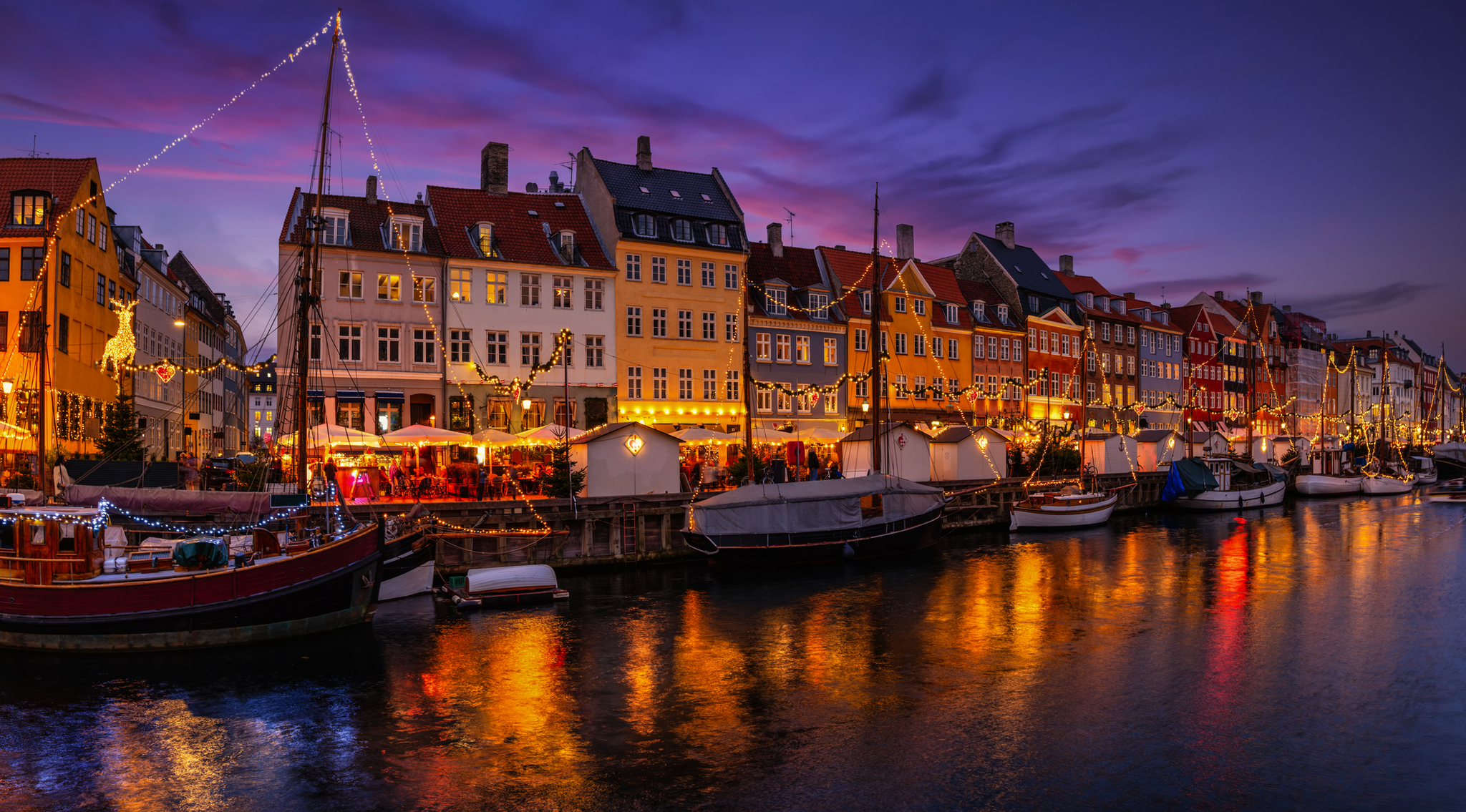 Abendstimmung mit beleuchteten Häusern und Booten an einem Kanal.