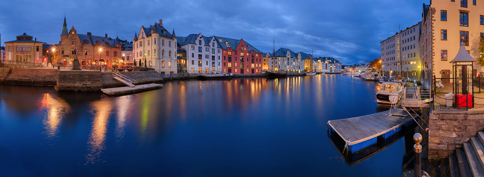 Bunte Häuser am Wasser in einer Stadt bei Dämmerung.