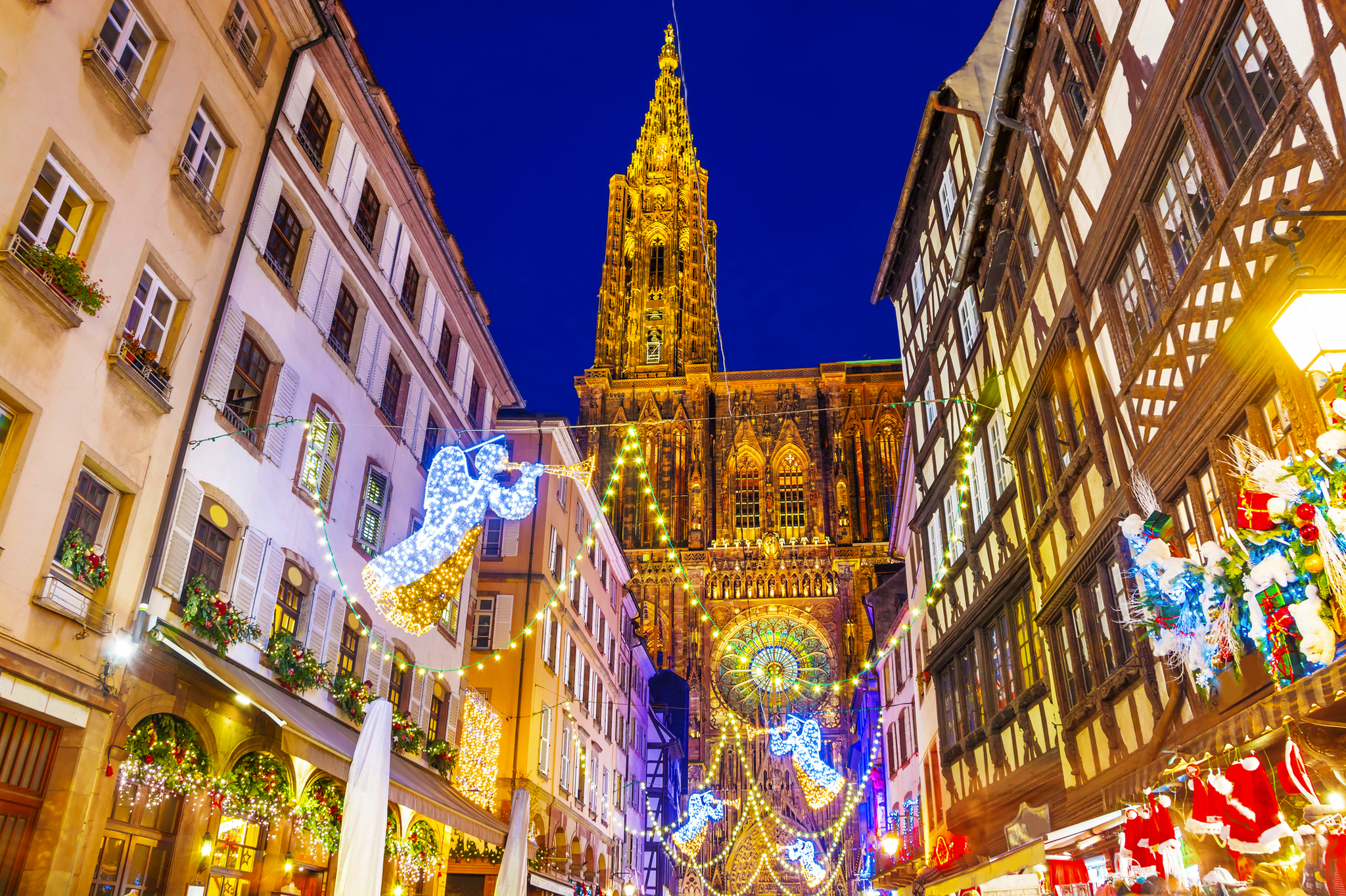 Straßenszene mit beleuchteter Kathedrale und Weihnachtsdekorationen am Abend.