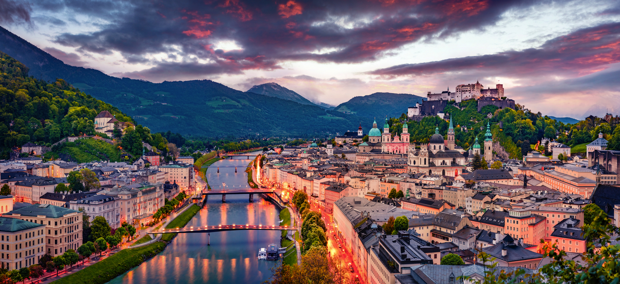Stadtansicht von Salzburg mit Burg im Hintergrund bei Sonnenuntergang.