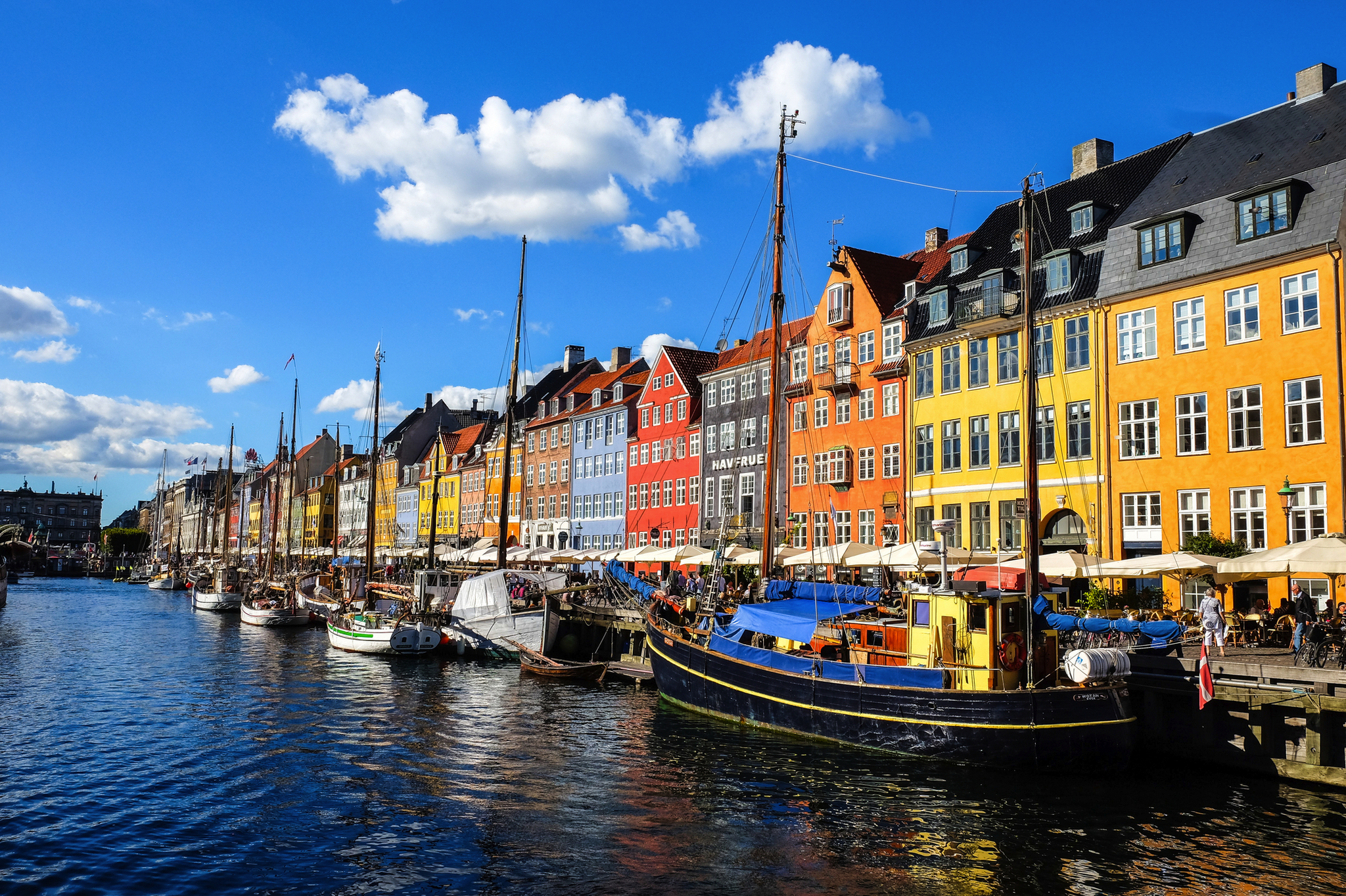 Bunte Häuserreihe am Wasser mit Segelbooten unter blauem Himmel.