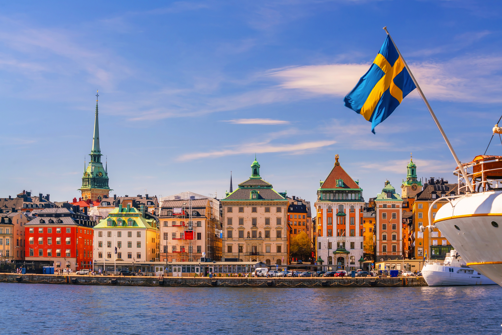 Blick auf Stockholm mit Gebäuden und schwedischer Flagge bei sonnigem Wetter.