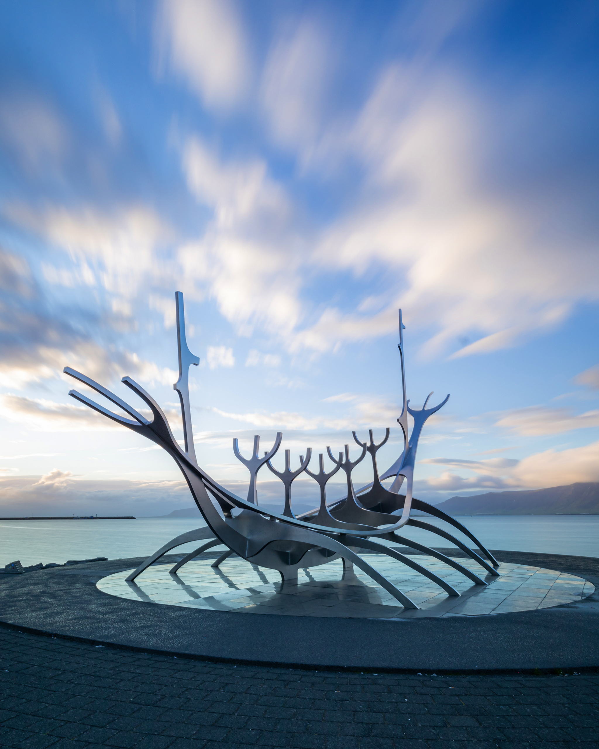 Skulptur eines stilisierten Wikingerboots am Meer unter blauem Himmel.