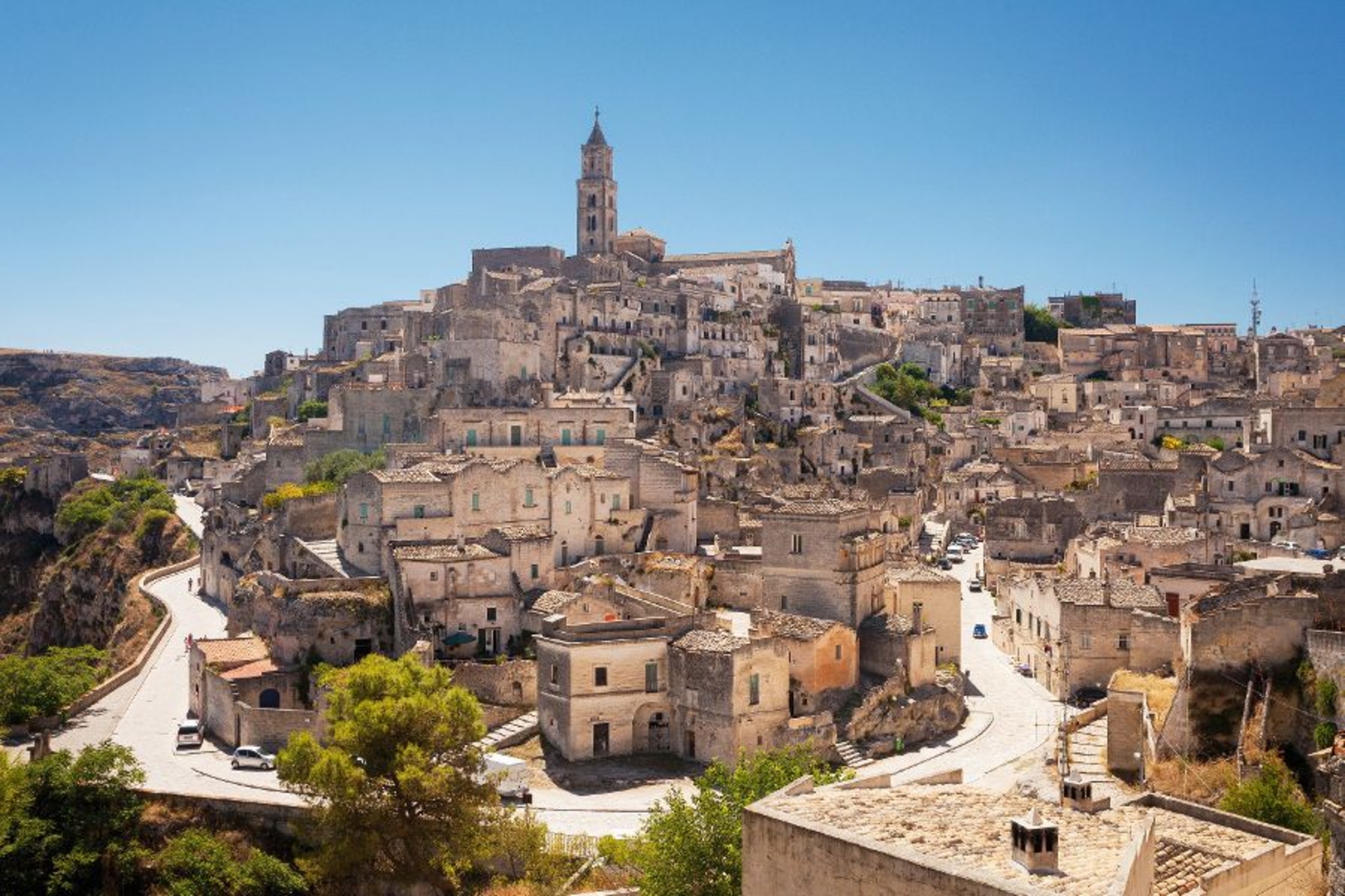 Historische italienische Stadt mit alten Gebäuden auf einem Hügel unter blauem Himmel.
